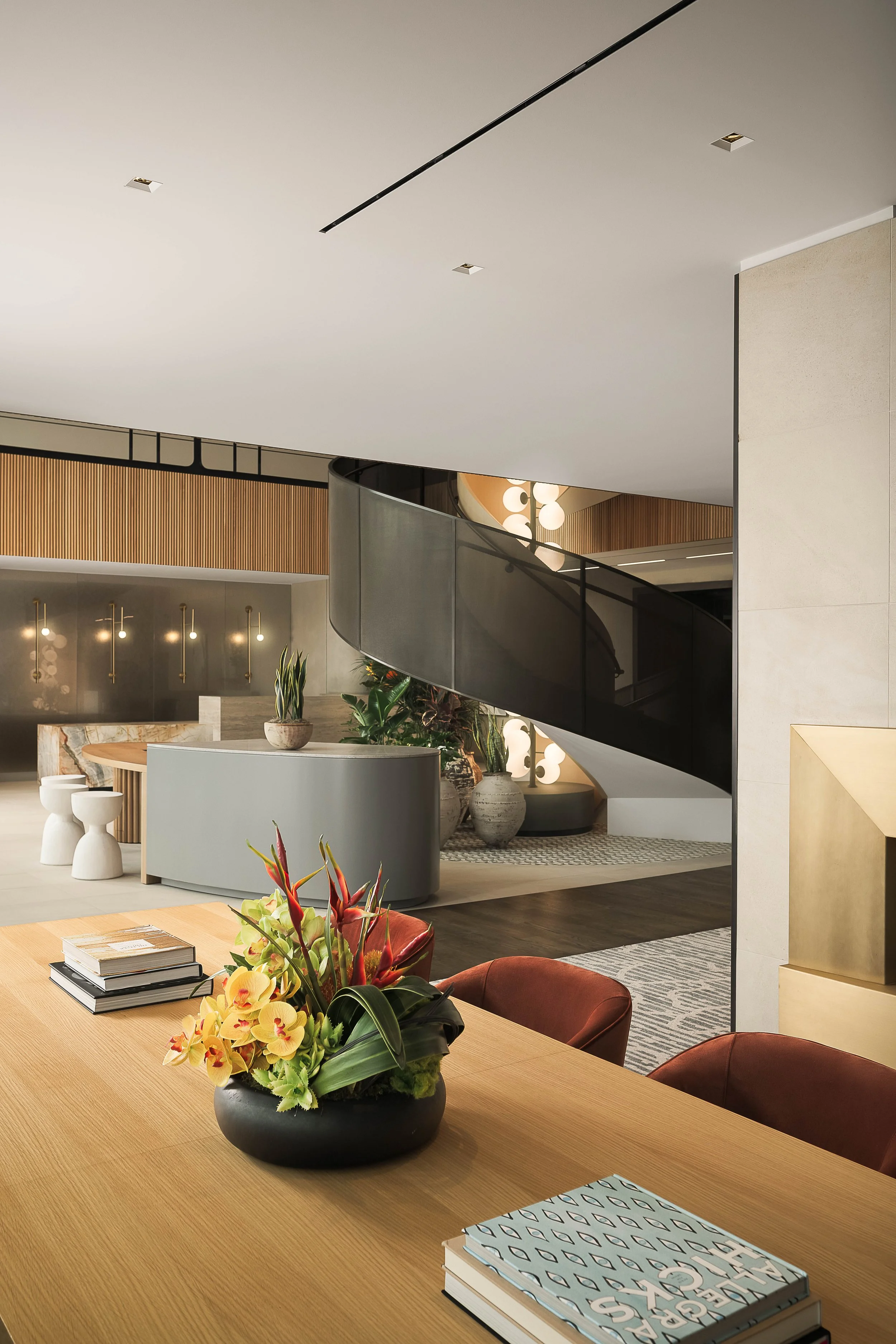 Modern leasing reception with warm wood slat wall, fresh floral arrangement, and refined furnishings — luxury commercial interior photography, Los Angeles CA