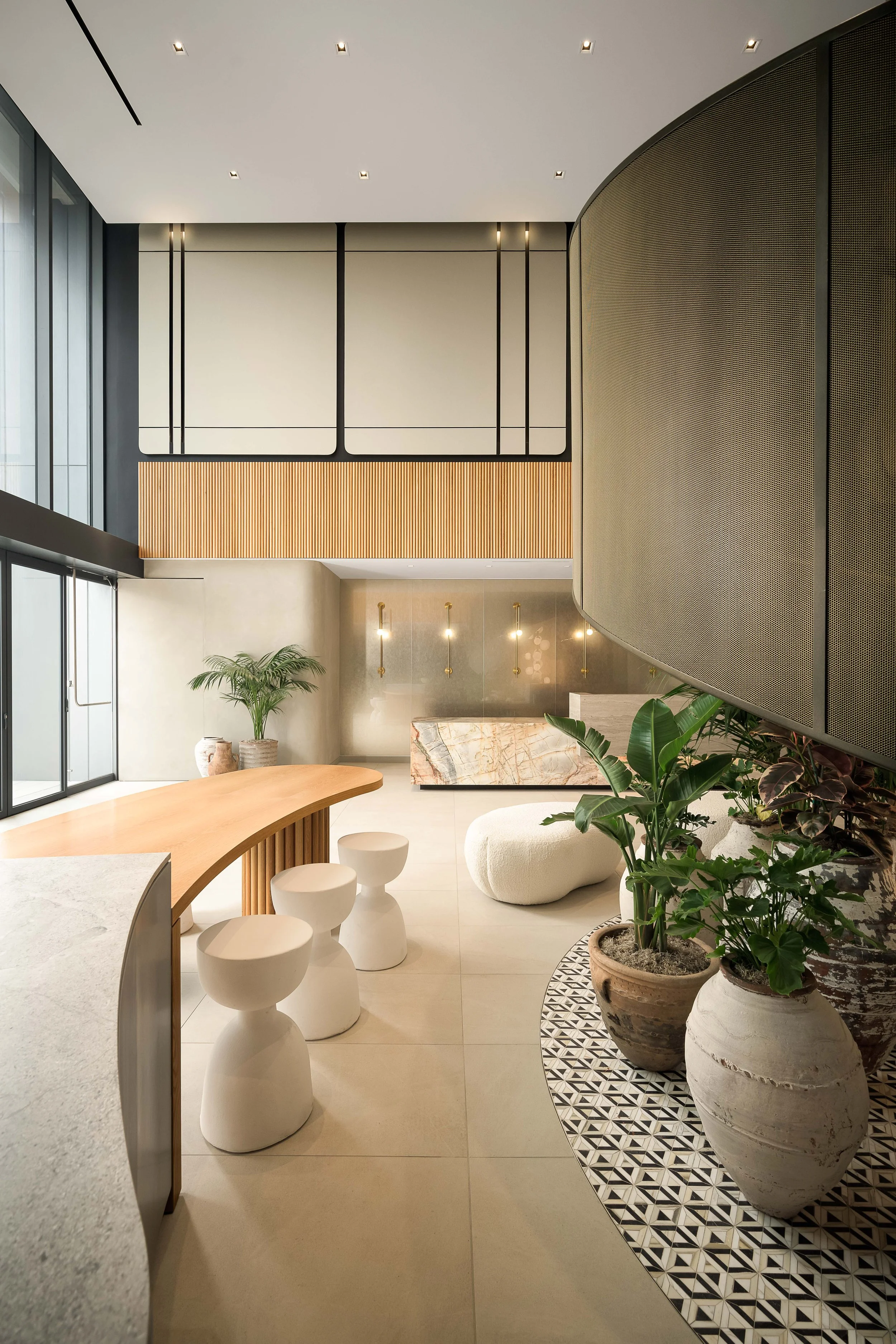 Lobby with curved graphic tile wall, sculptural bean stools, and lush tropical plants — commercial interior design photography, Entrada Los Angeles CA