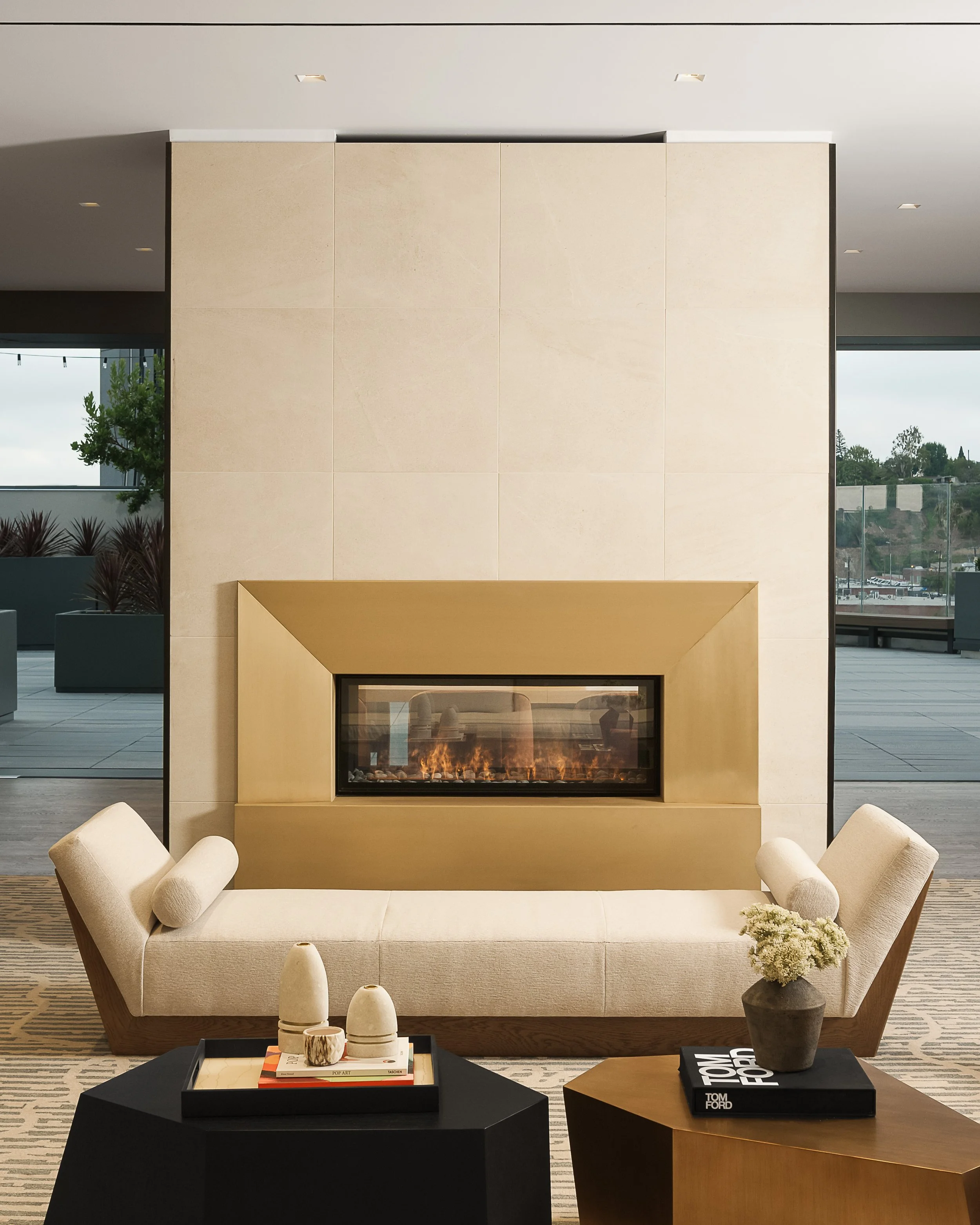 Light-filled lounge with recessed linear fireplace, linen sofas, and views through floor-to-ceiling glass — commercial architecture photography, Los Angeles CA