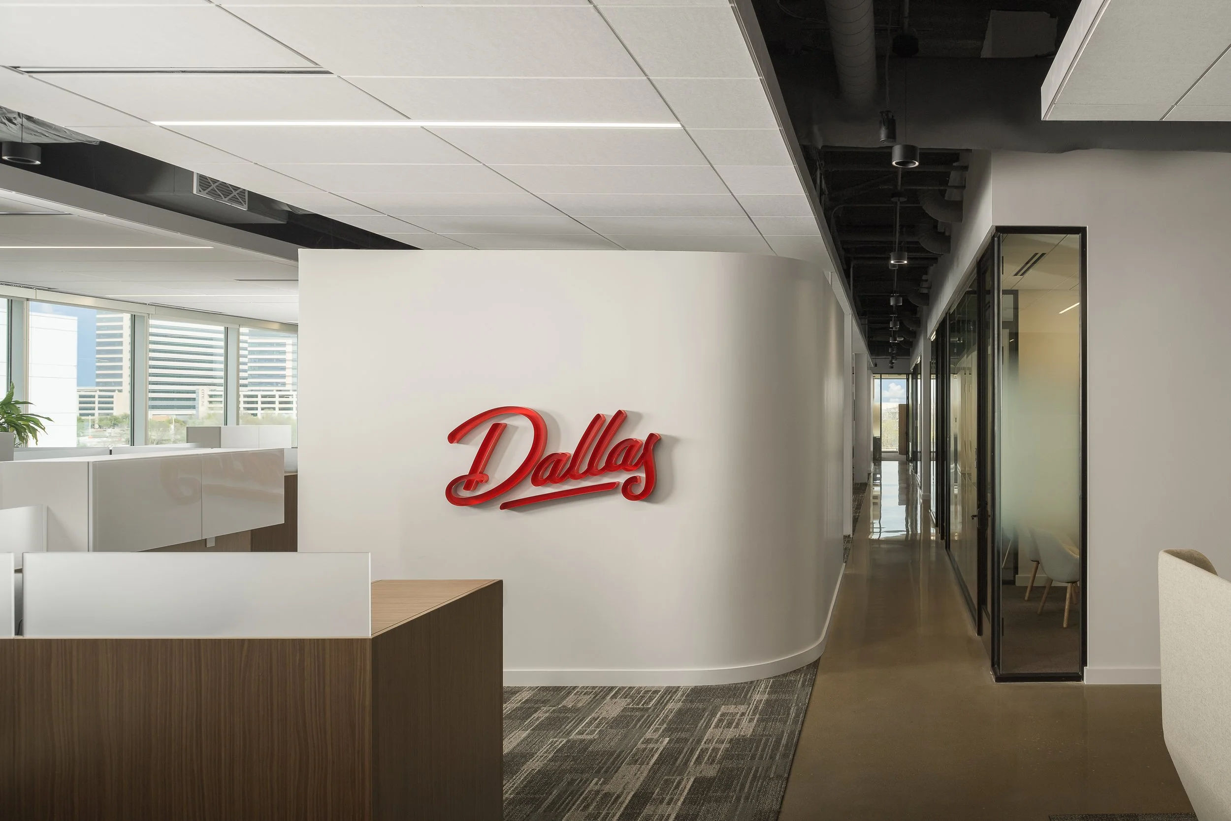 Office corridor reception with Dallas neon sign and curved welcome desk — corporate interior photography, McCarthy Building Companies Richardson TX
