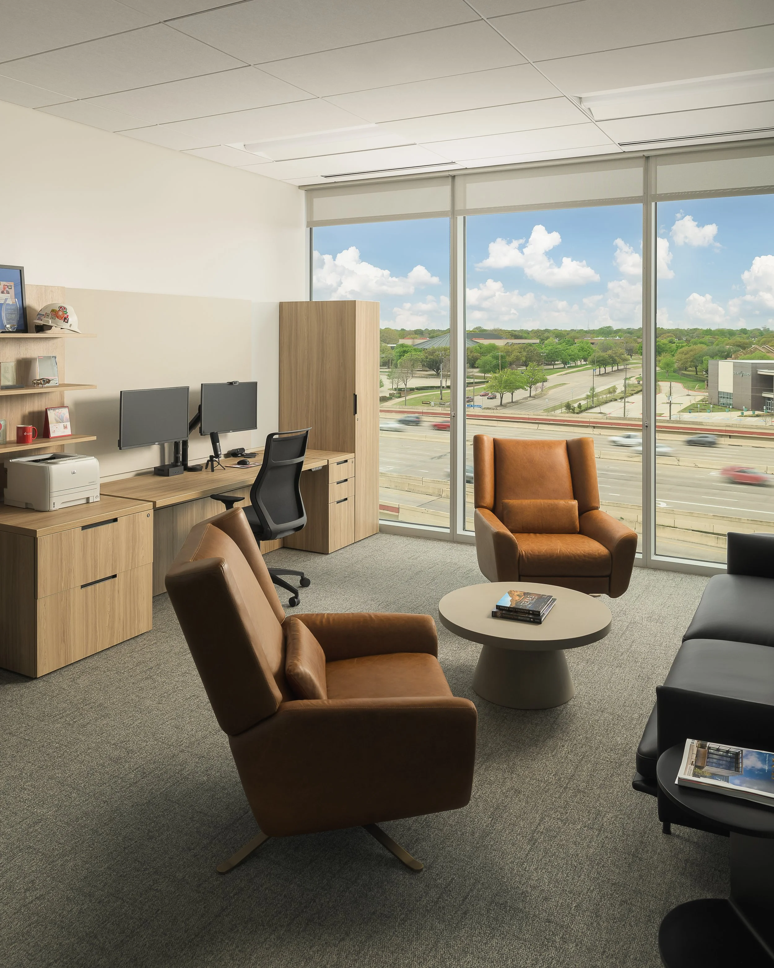 Corner office with leather chairs, daylight views across suburban landscape, and casual work setting — corporate interior photography, Richardson TX