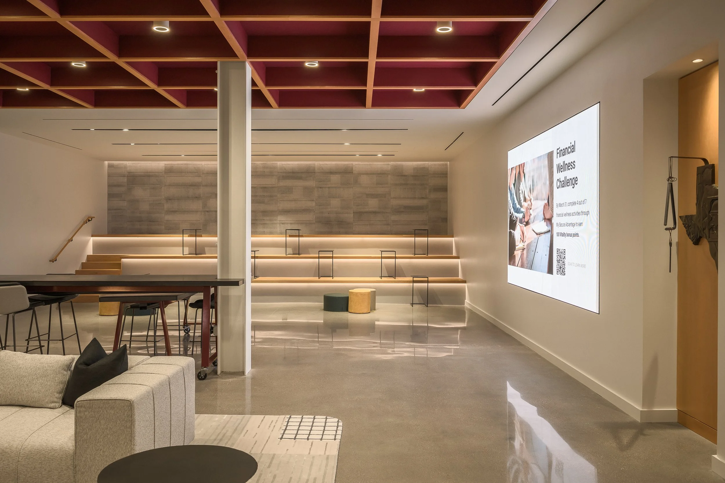 Collaborative office atrium with large digital display wall and stepped tiered seating area — corporate architecture photography, McCarthy Building Companies TX