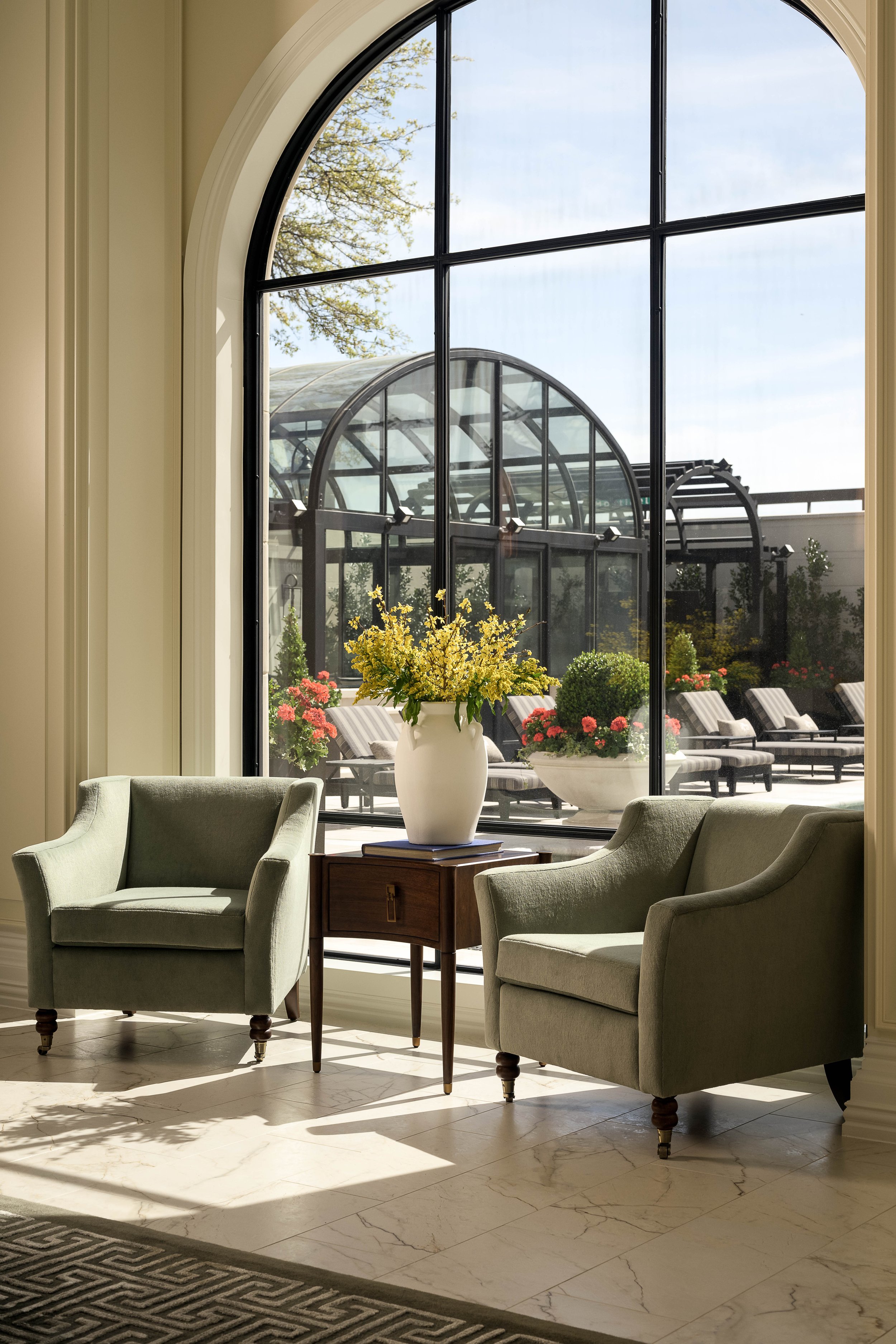 Sunlit residential sitting room with floor-to-ceiling arched greenhouse window and fresh floral arrangement — luxury interior photography, Dallas TX
