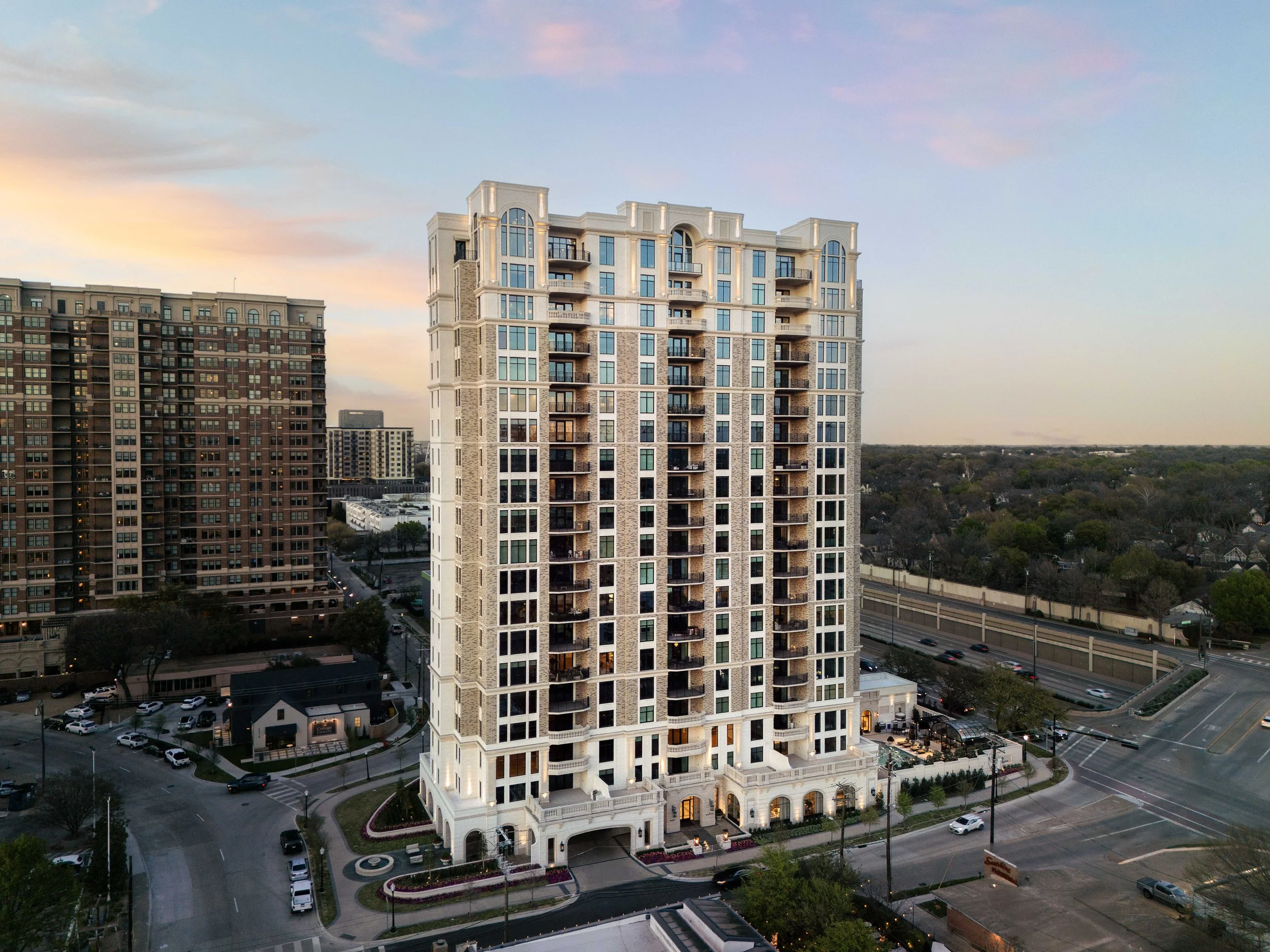 Drone aerial view of neoclassical residential tower at sunset, Dallas TX skyline — luxury architecture photography