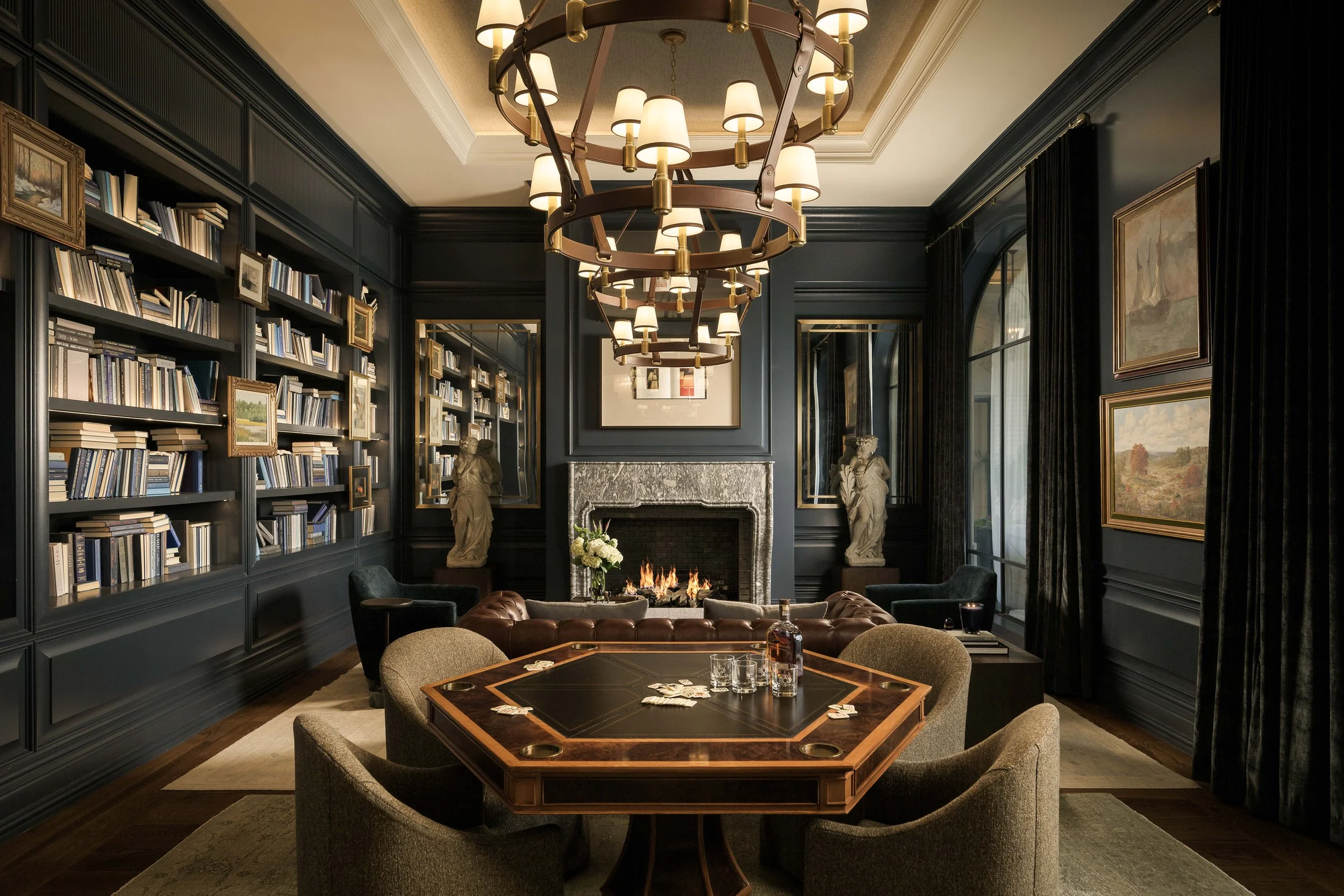 Dark moody library with built-in bookshelves, fireplace, and octagonal game table — residential interior photography