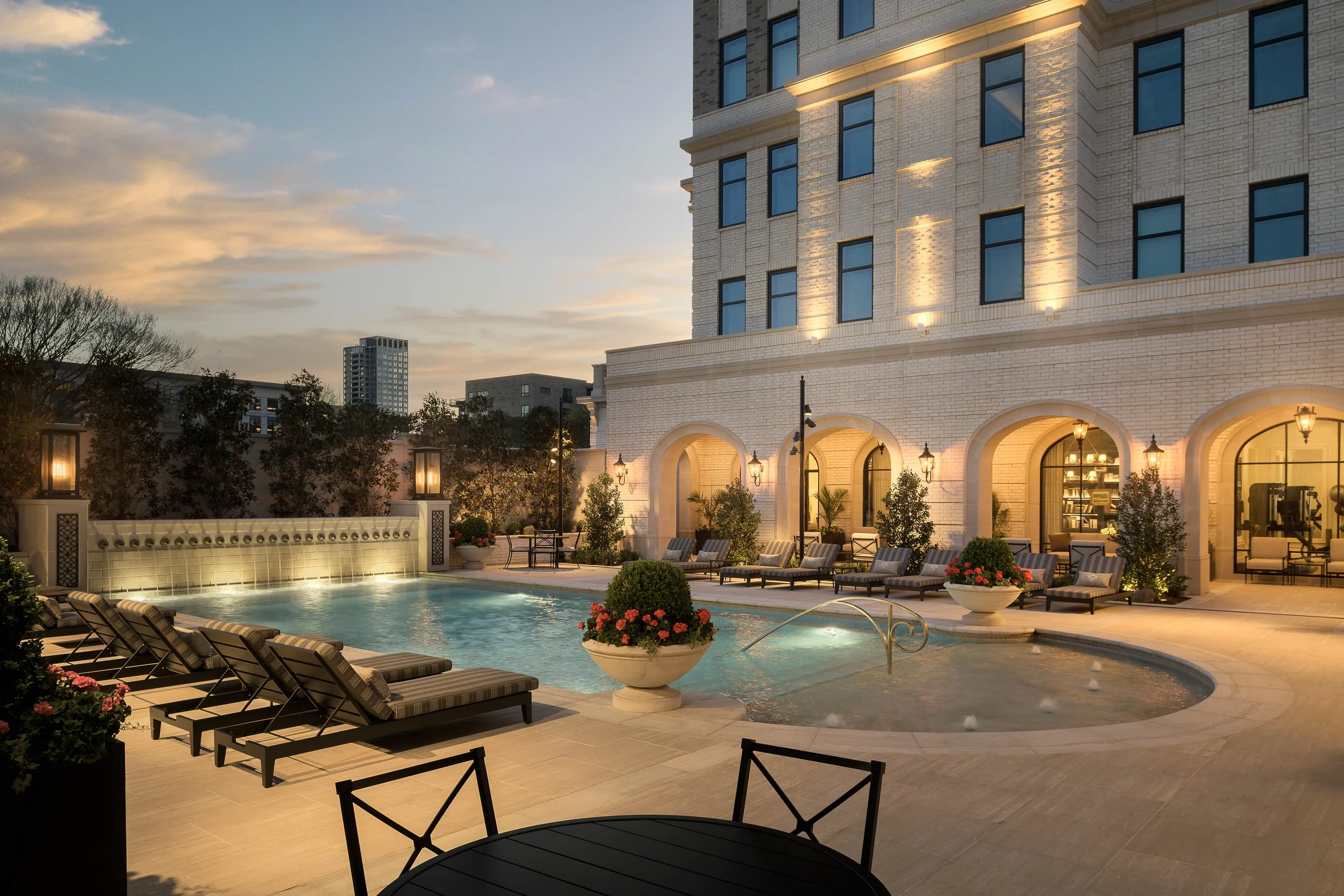 Luxury hotel exterior at dusk with illuminated arched facade and pool terrace — commercial architecture photography Phoenix AZ
