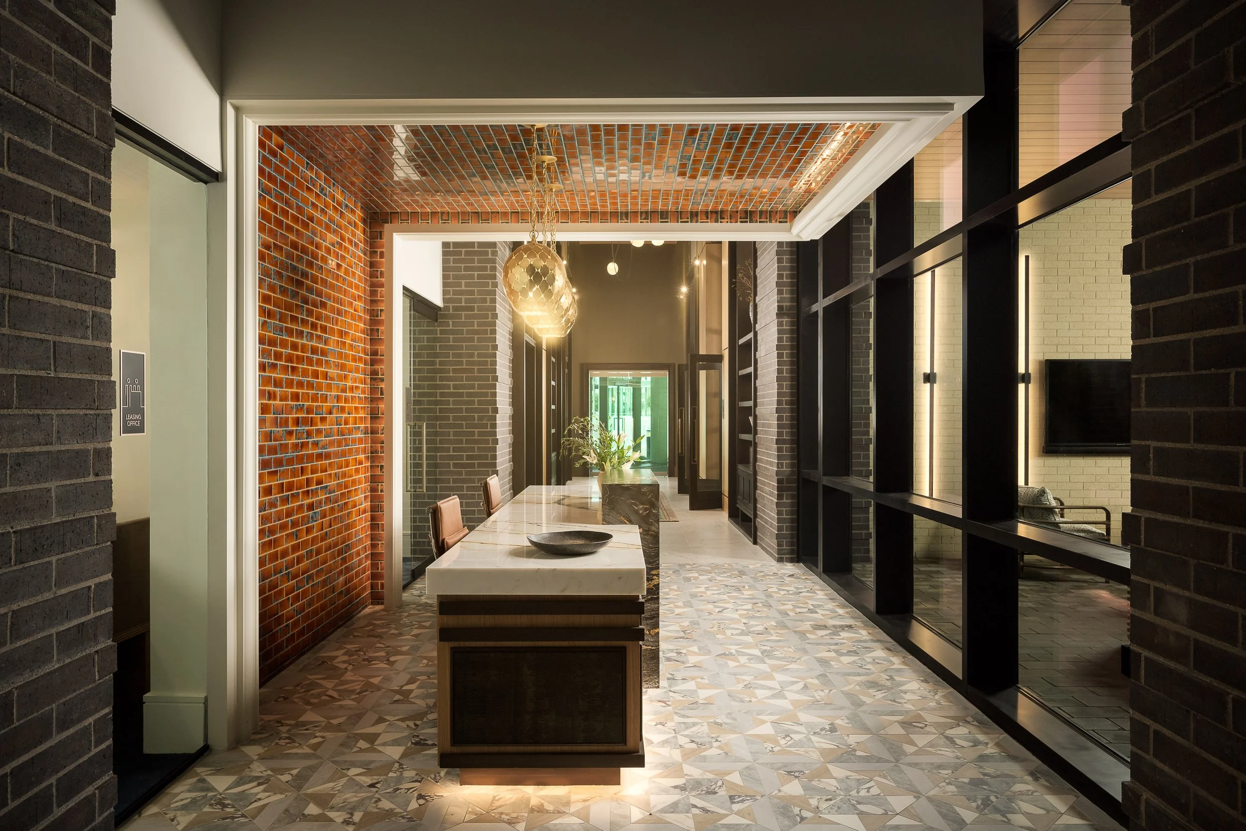 Brick-accented kitchen corridor with exposed ceiling, pendant fixtures, and polished concrete floors — contemporary apartment interior, The Oliver Dallas TX