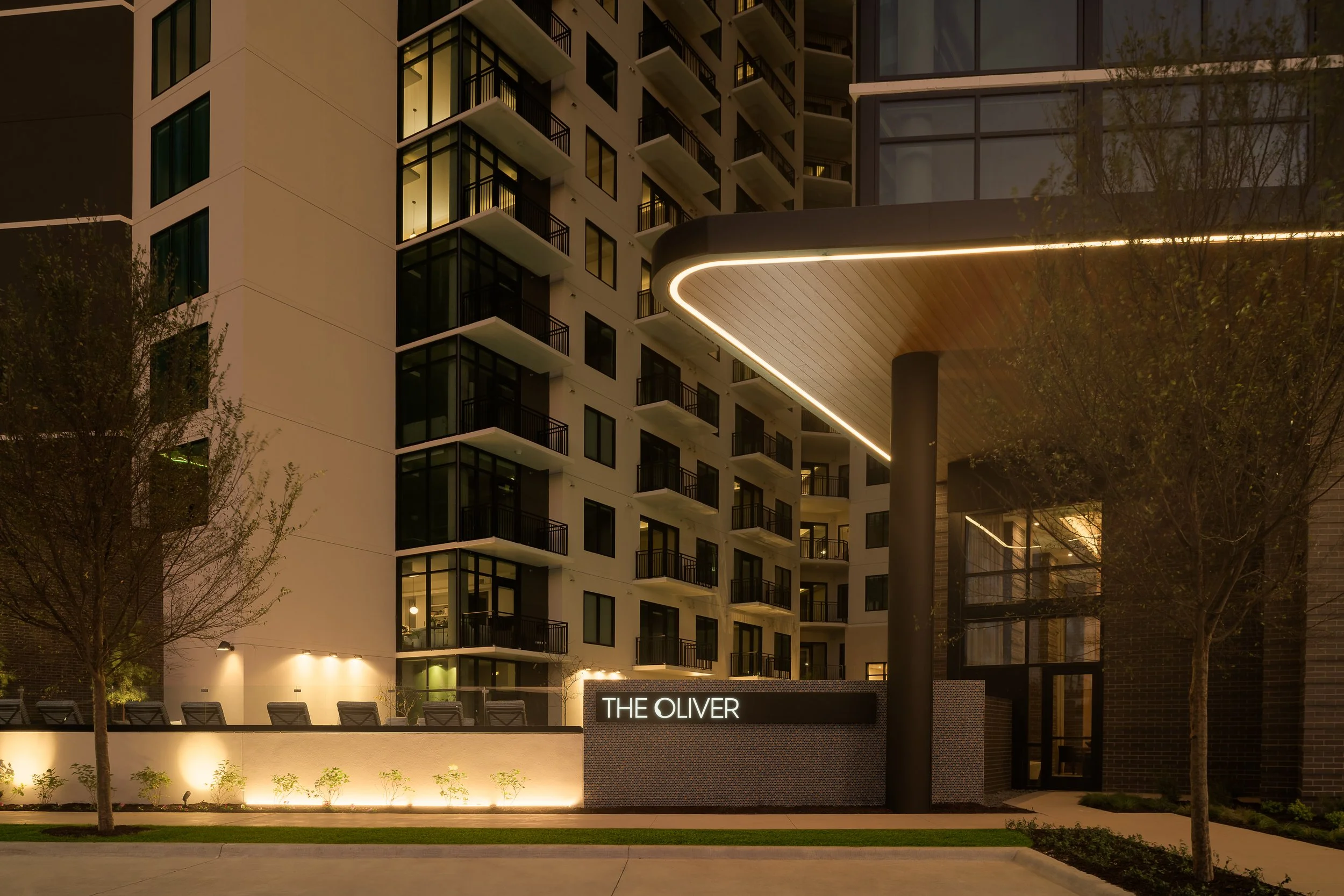 Night exterior detail of luxury residential tower with Oliver signage and modern cladding — architecture photography, Dallas TX