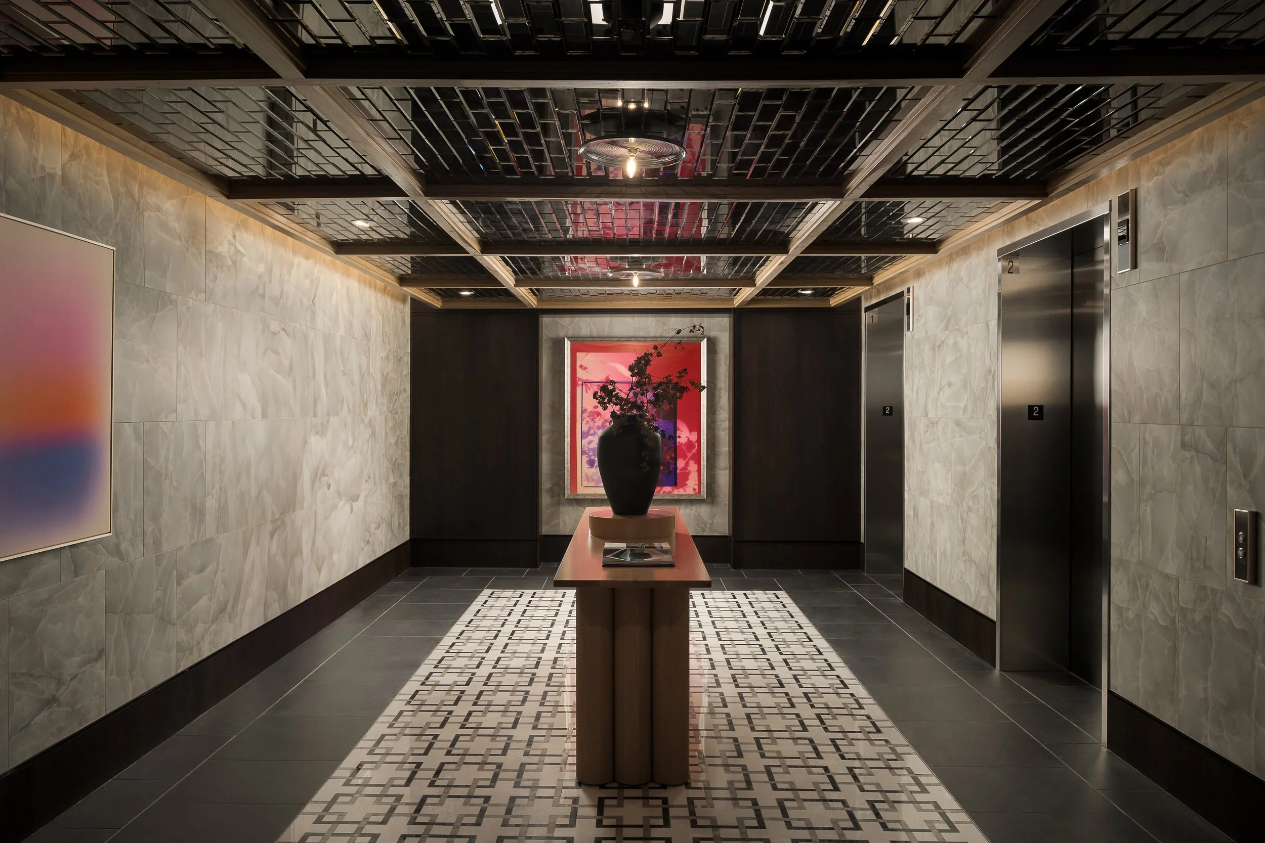 Dramatic dark corridor with coffered ceiling, framed artwork, and woven runner rug — luxury apartment common area design, The Oliver Dallas TX