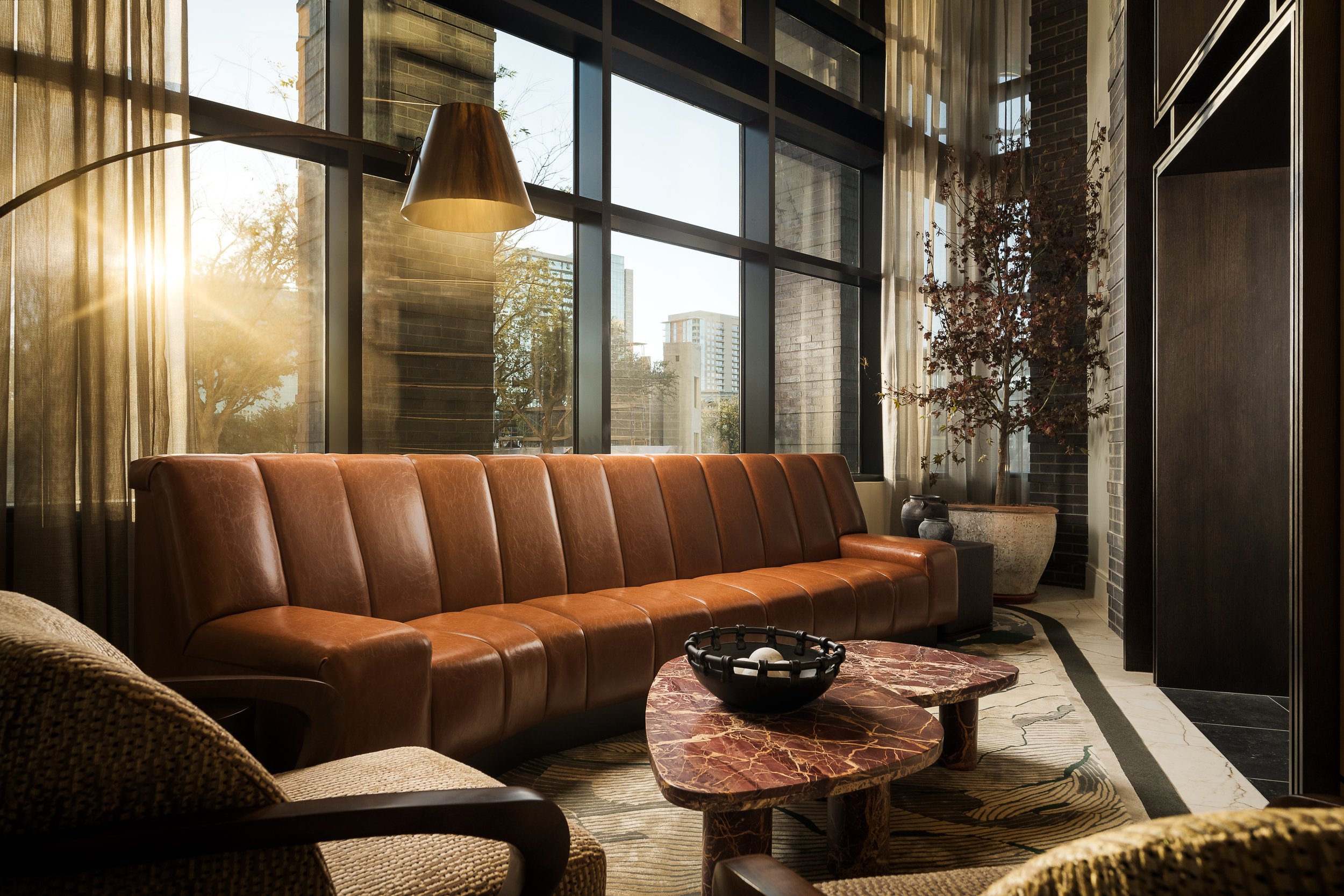 Luxury apartment lounge with leather sofa, floor-to-ceiling windows, and city views — contemporary interior design, The Oliver Dallas TX