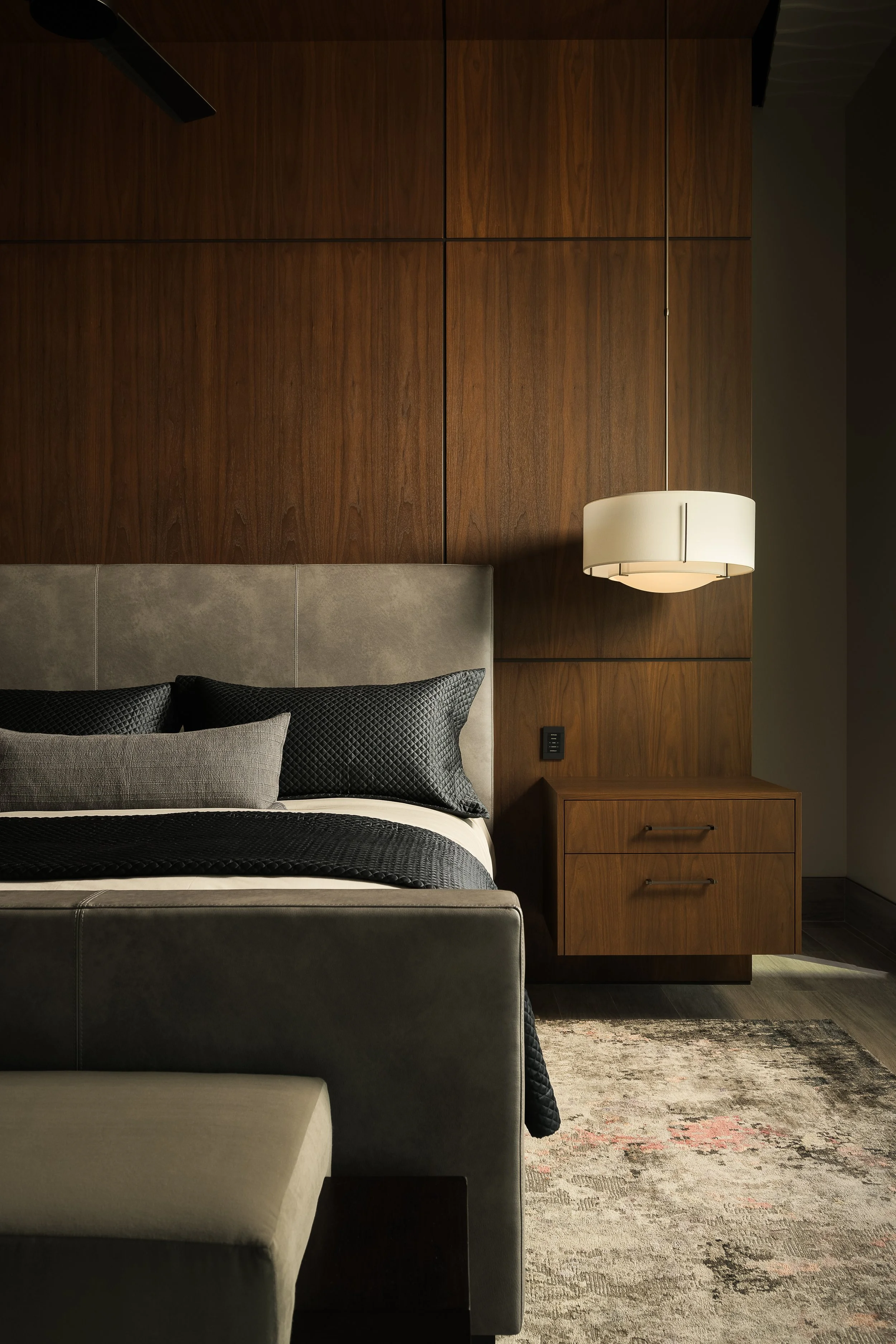 Modern hotel bedroom with dark tones, pendant lighting, and curated art — hospitality interior photography