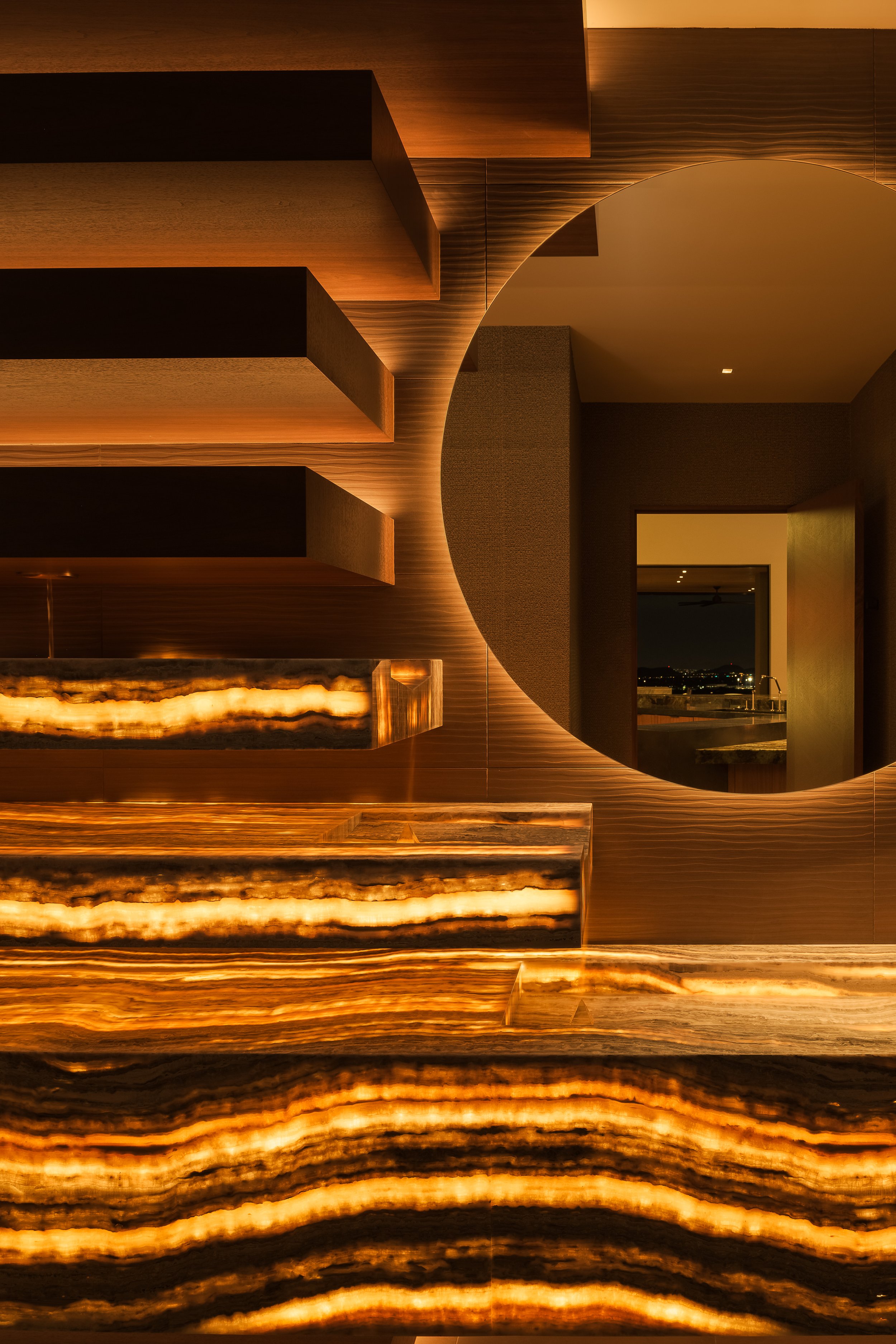 Contemporary residential foyer with illuminated wood wall and dramatic circular detail — luxury interior photography