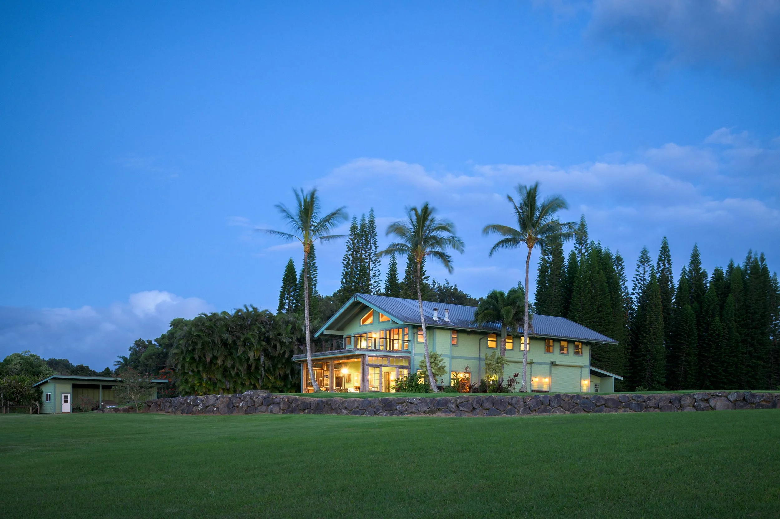 Luxury ranch home exterior at twilight with palm trees and warm lighting — residential architecture photography Maui Hawaii