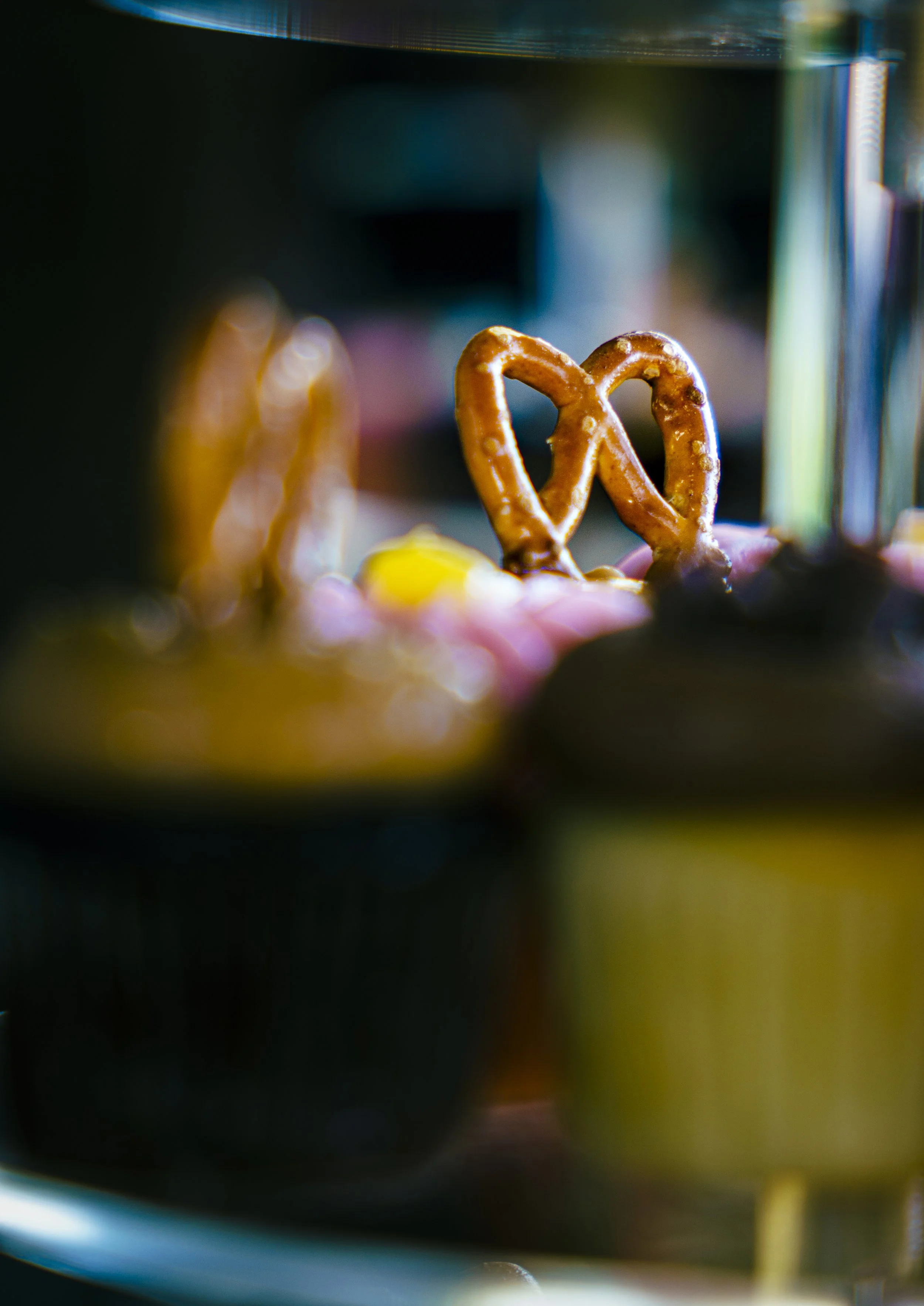 Close-up of a pretzel with a glossy surface in front of blurred colorful background.
