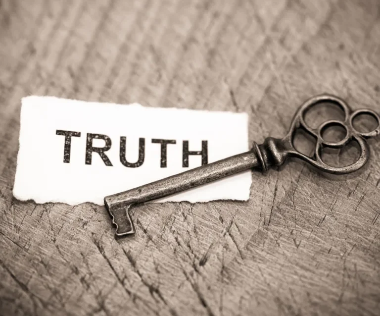 A vintage key placed next to a torn piece of paper with the word 'TRUTH' printed on it.