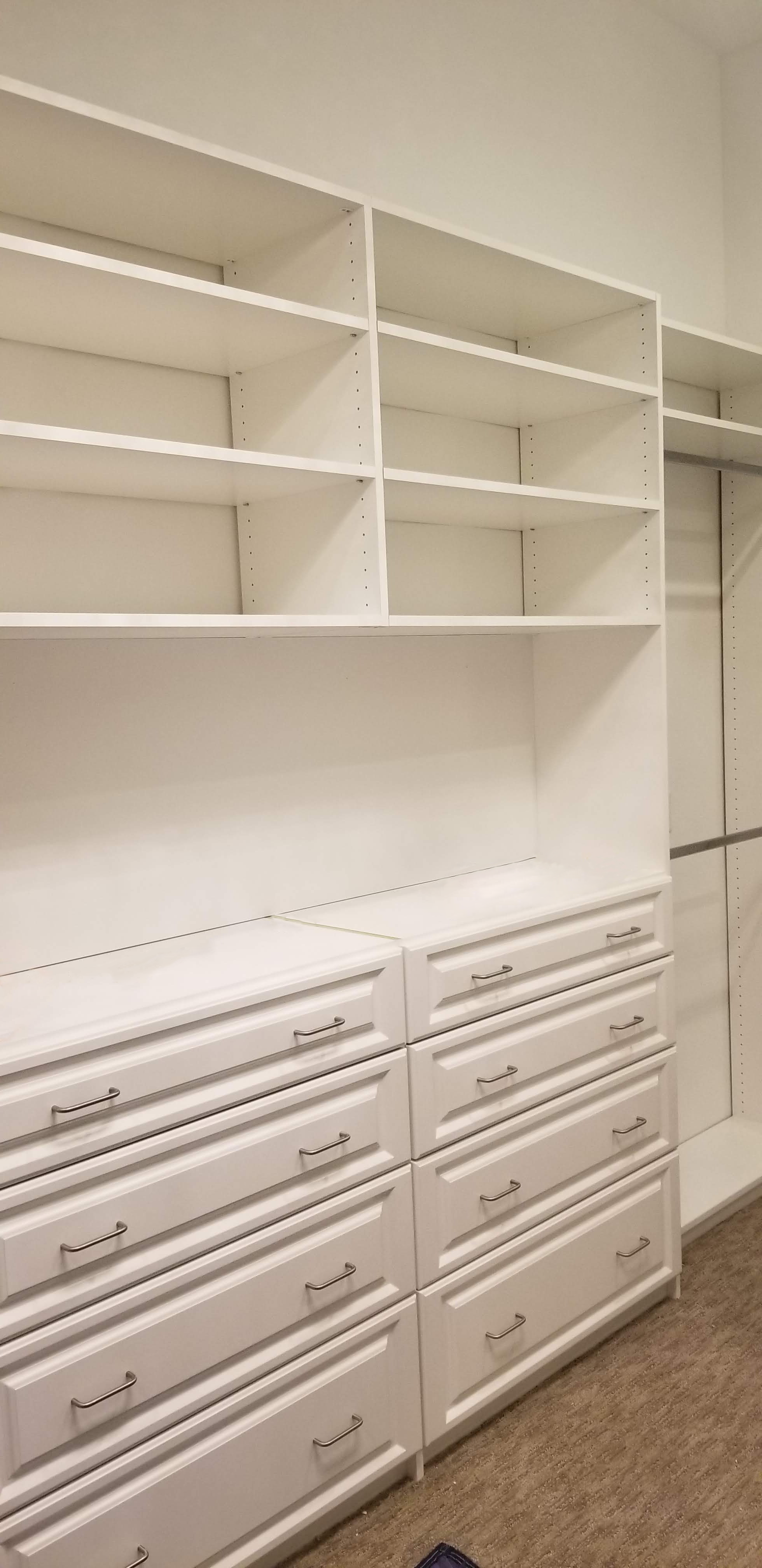 Custom built walk-in closet in Irving with white shelving, integrated clothing rods, soft close doors and sleek hardware.