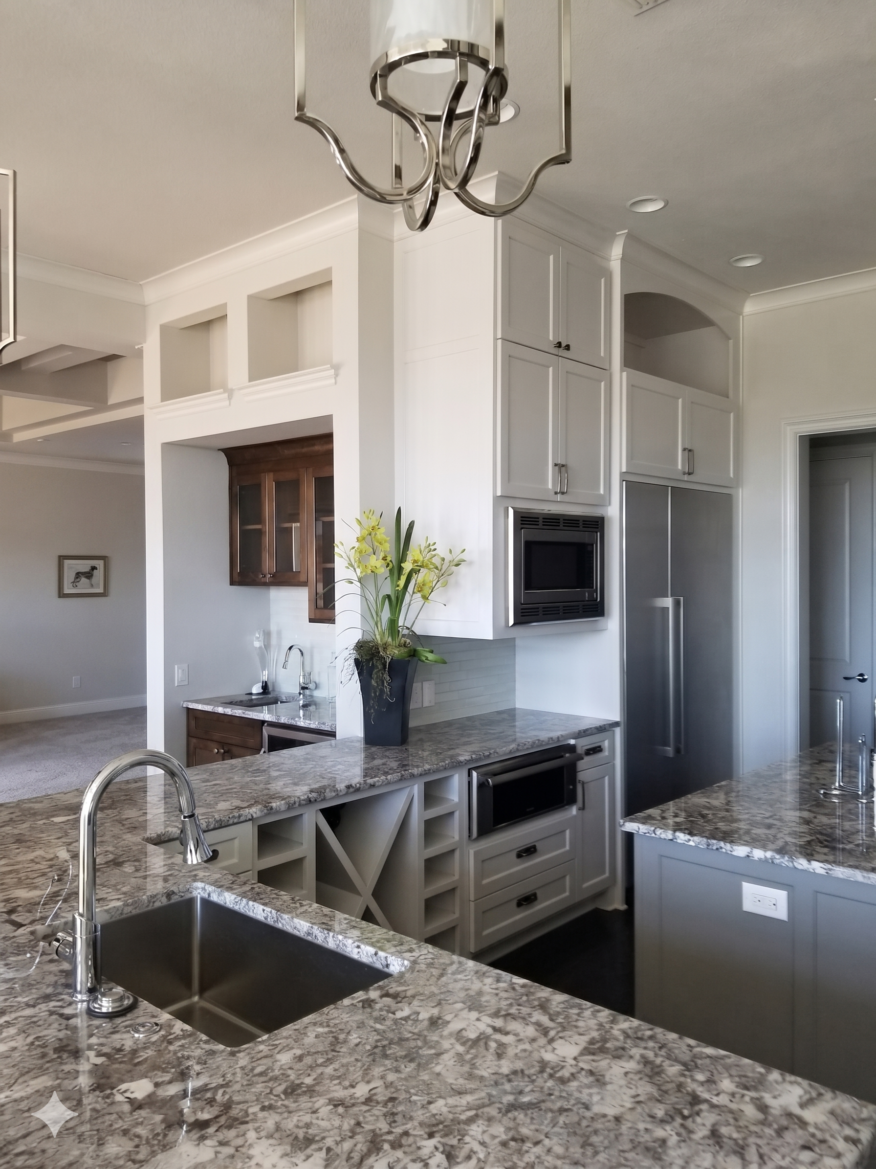 Inside shot of a luxury custom kitchen in Grapevine, featuring expansive granite countertops, open wine rack shelves, and built-in appliances.