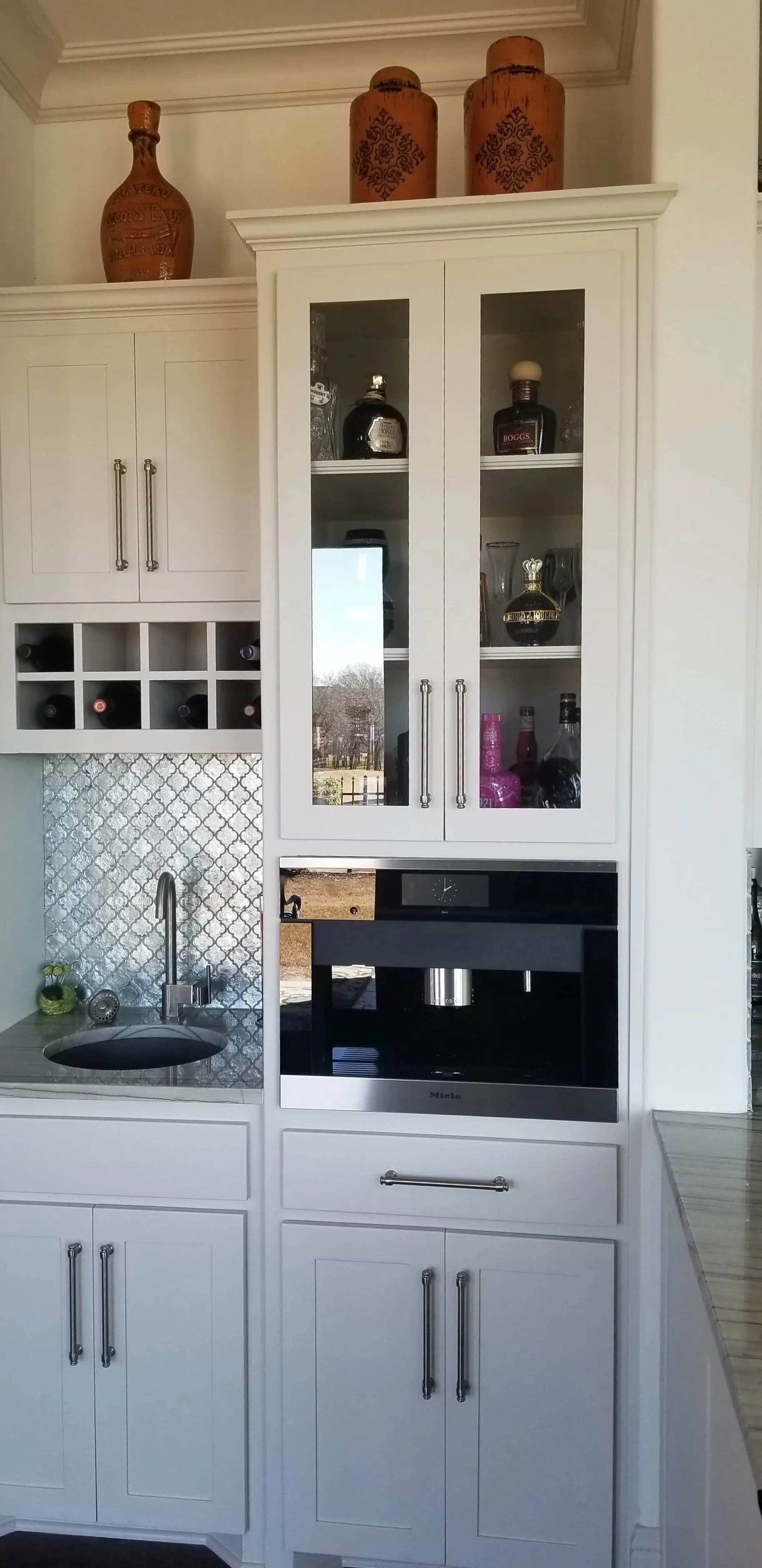 Custom wet bar in Grapevine with wine storage, prep sink, mosaic backsplash, and an integrated Miele espresso machine.