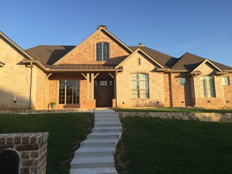Exterior of a rustic, craftsman style luxury home in Fort Worth. Expertly crafted stone and brick blend together to create this earthy while at the same time premium look.