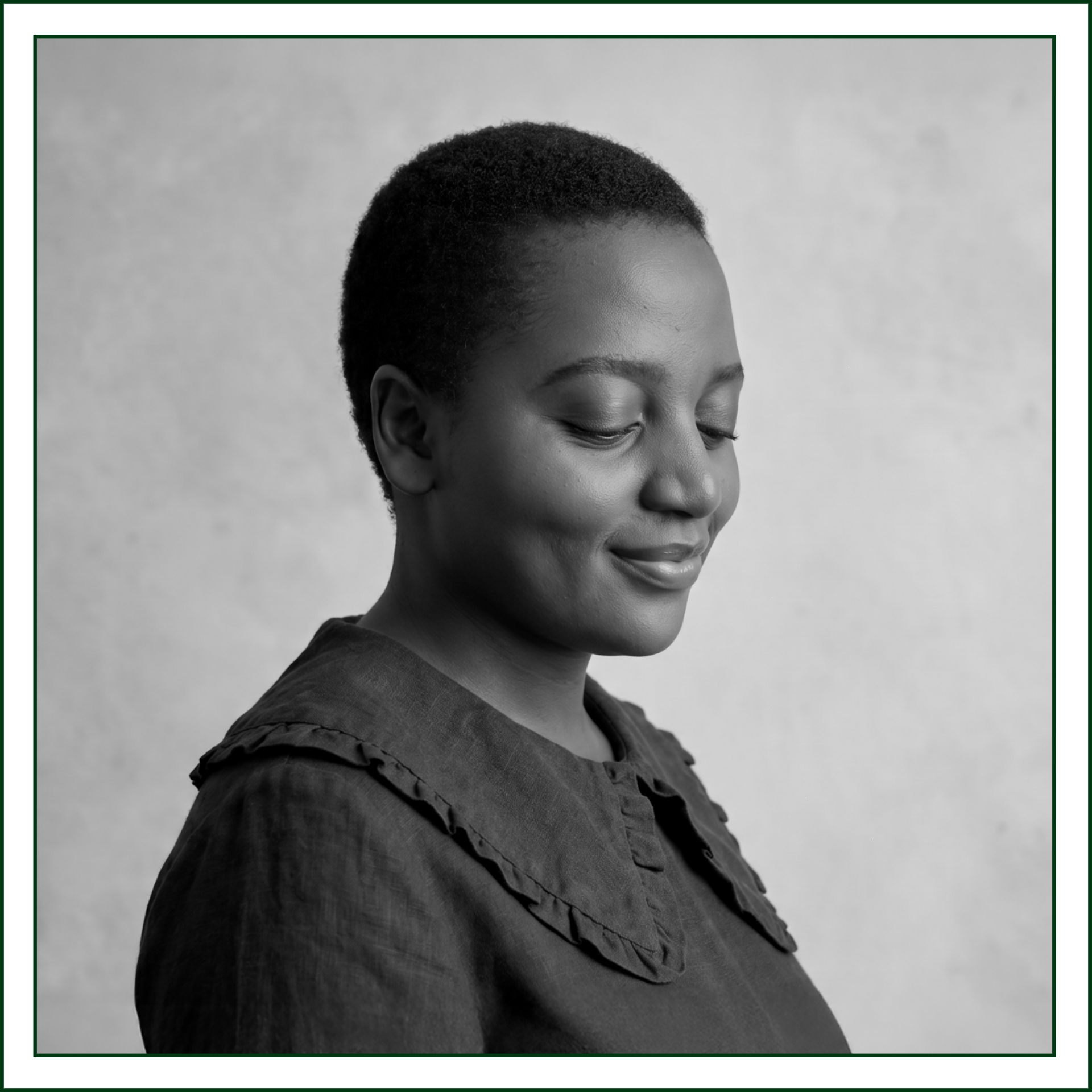 Black and white portrait of Lillian Ingabire of Studio Kalili, an editorial branding studio, in a ruffle-collar top with eyes gently closed