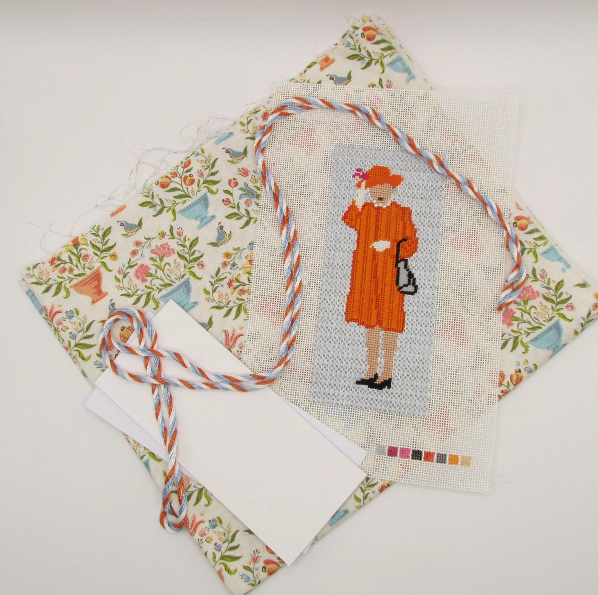 Cross-stitched orange foxes on white Aida cloth, with quilting fabric behind and twisted red, white, and blue thread