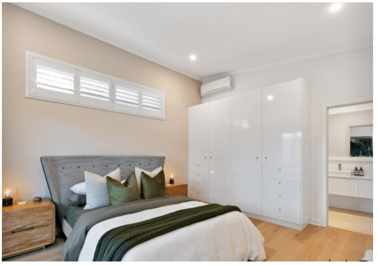 Modern bedroom with a bed, pillows, bedside tables, and wardrobes.