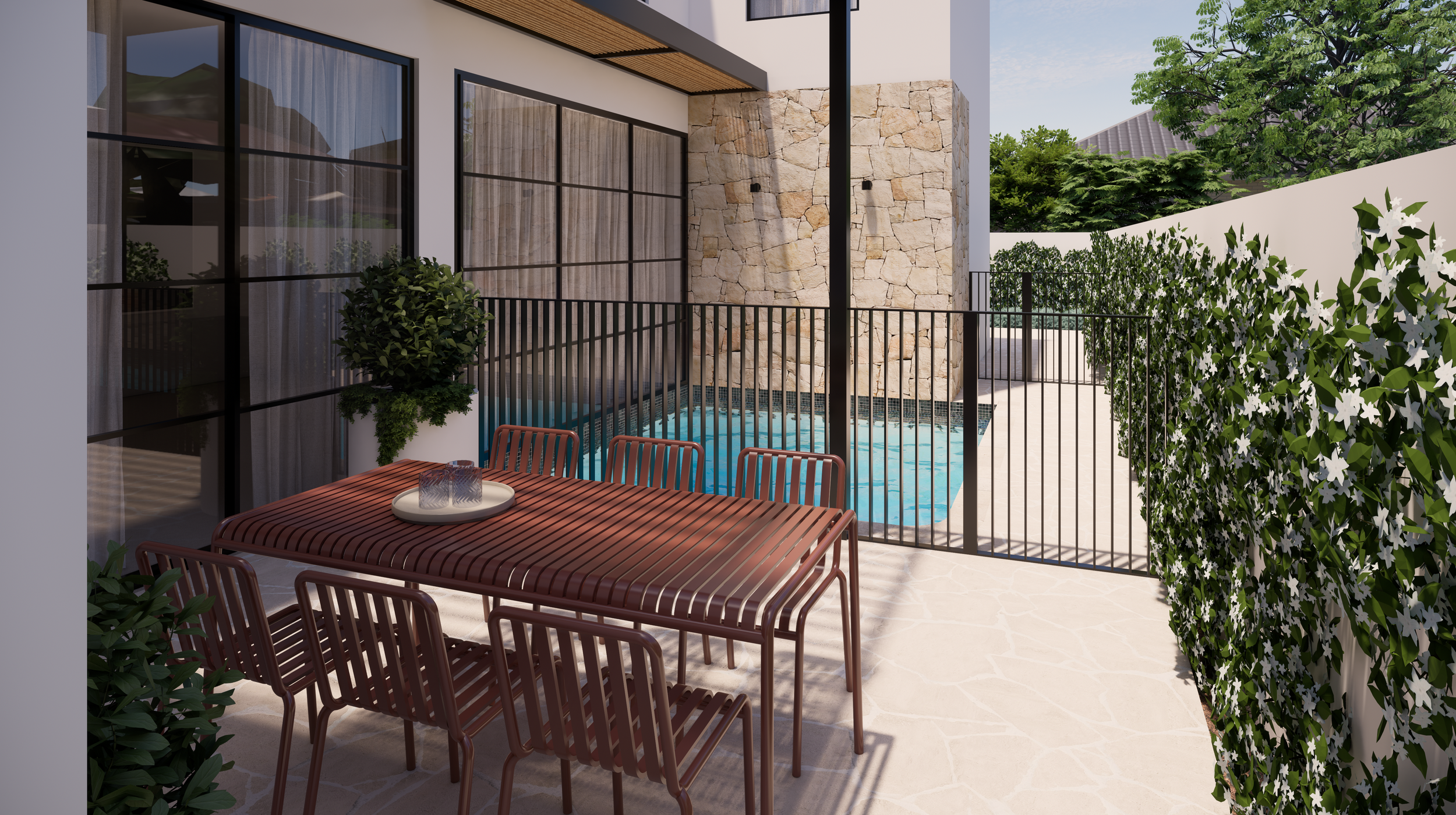 An outdoor patio with a wooden dining table and chairs, a small pool, a stone wall, and lush greenery including bushes andtrees.
