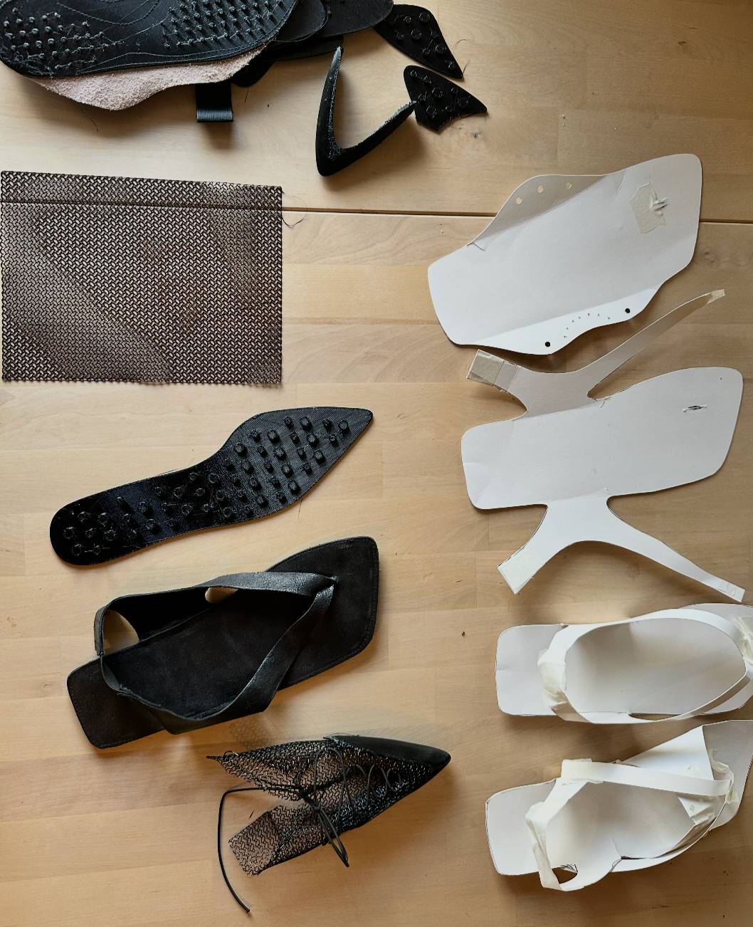 Various shoe parts and accessories, including insoles, soles, mesh fabric, and shoe molds, arranged on a light wooden surface.