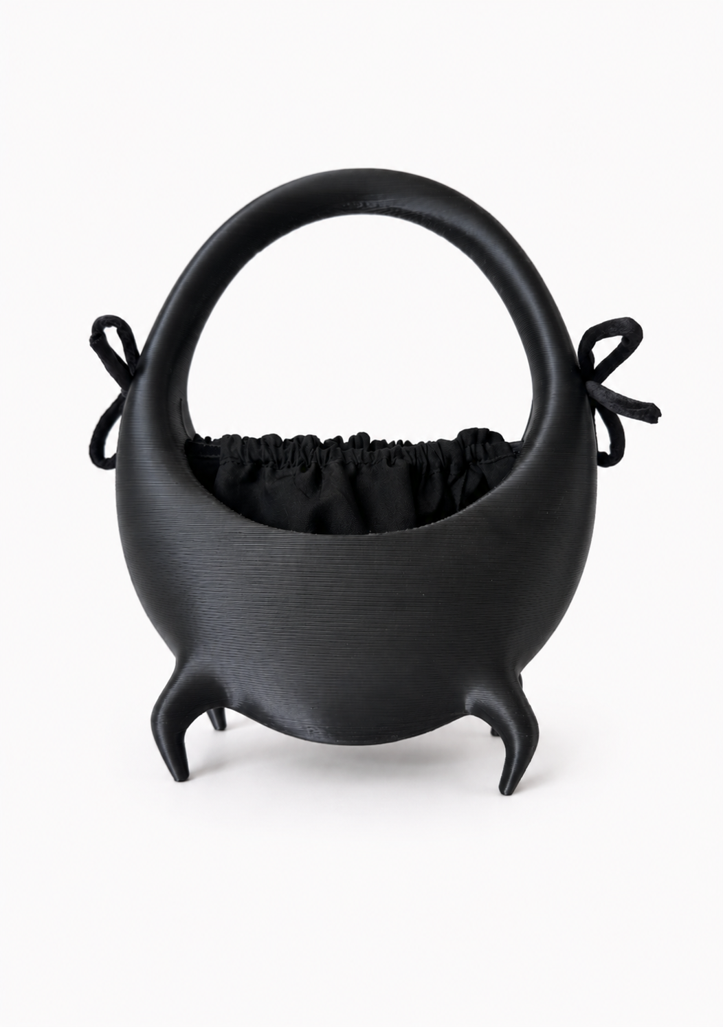 A black, modern, Artistic kettle with a handle and small legs, with a cloth pouch inside.