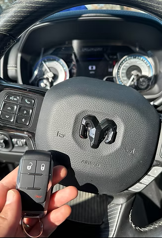 Kairo Lock and Key technician holding a Ram truck key fob inside the vehicle during an automotive locksmith service.