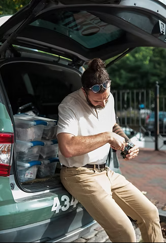 Kairo Lock and Key technician sitting at the back of a hatchback vehicle preparing tools during a mobile locksmith service call.