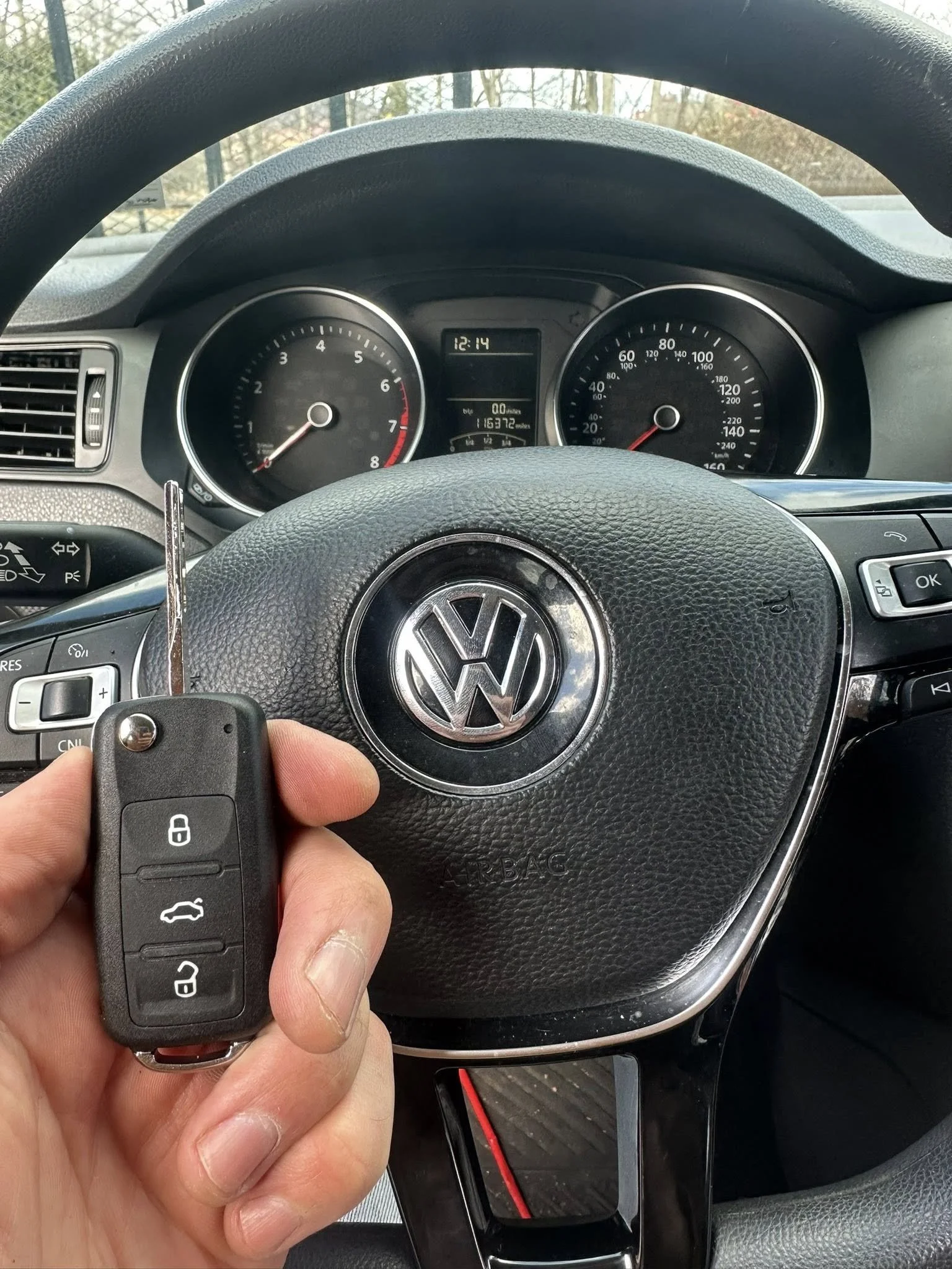 Kairo Lock and Key technician holding a Volkswagen key fob inside the vehicle during an automotive locksmith service.