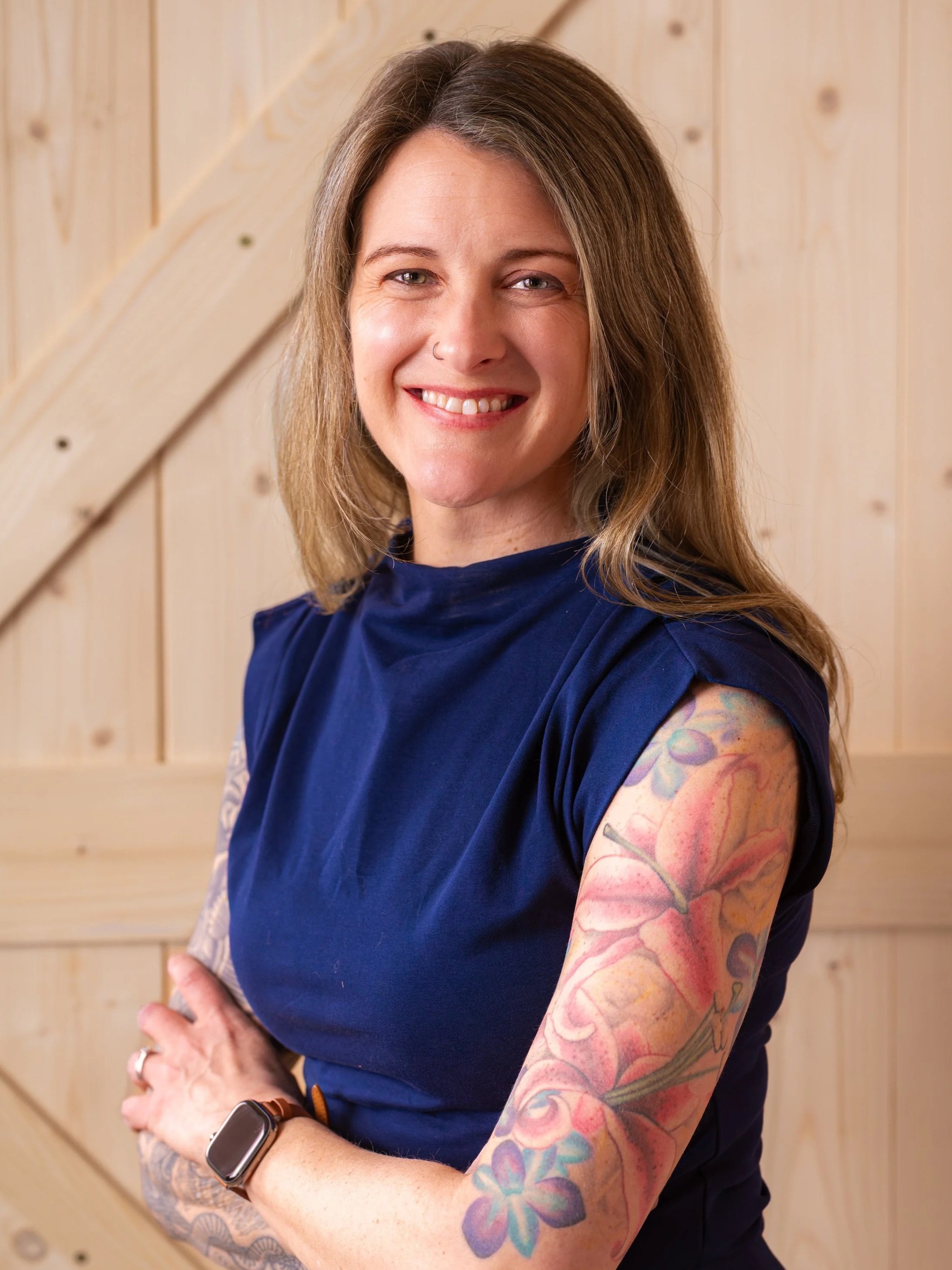 Smiling woman with tattoos offering Root-Cause Telehealth for mental health, metabolic health, weight loss, hormone therapy, and gut health via Telehealth in Alaska
