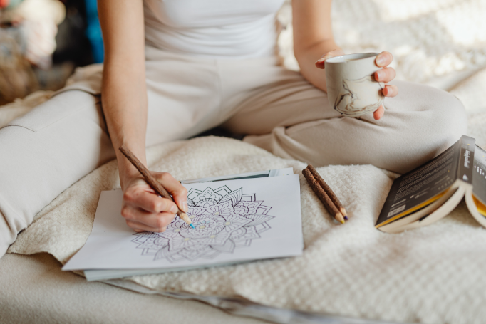Woman coloring a mandala drinking tea symbolizing art therapy and integrative psychiatry in Alaska