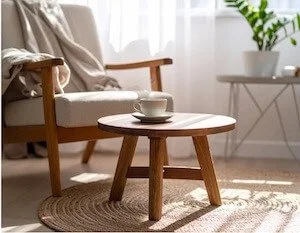 A wooden chair and table with a cup of tea and a blanket preparing for a therapeutic functional medicine telehealth appointment in Alaska