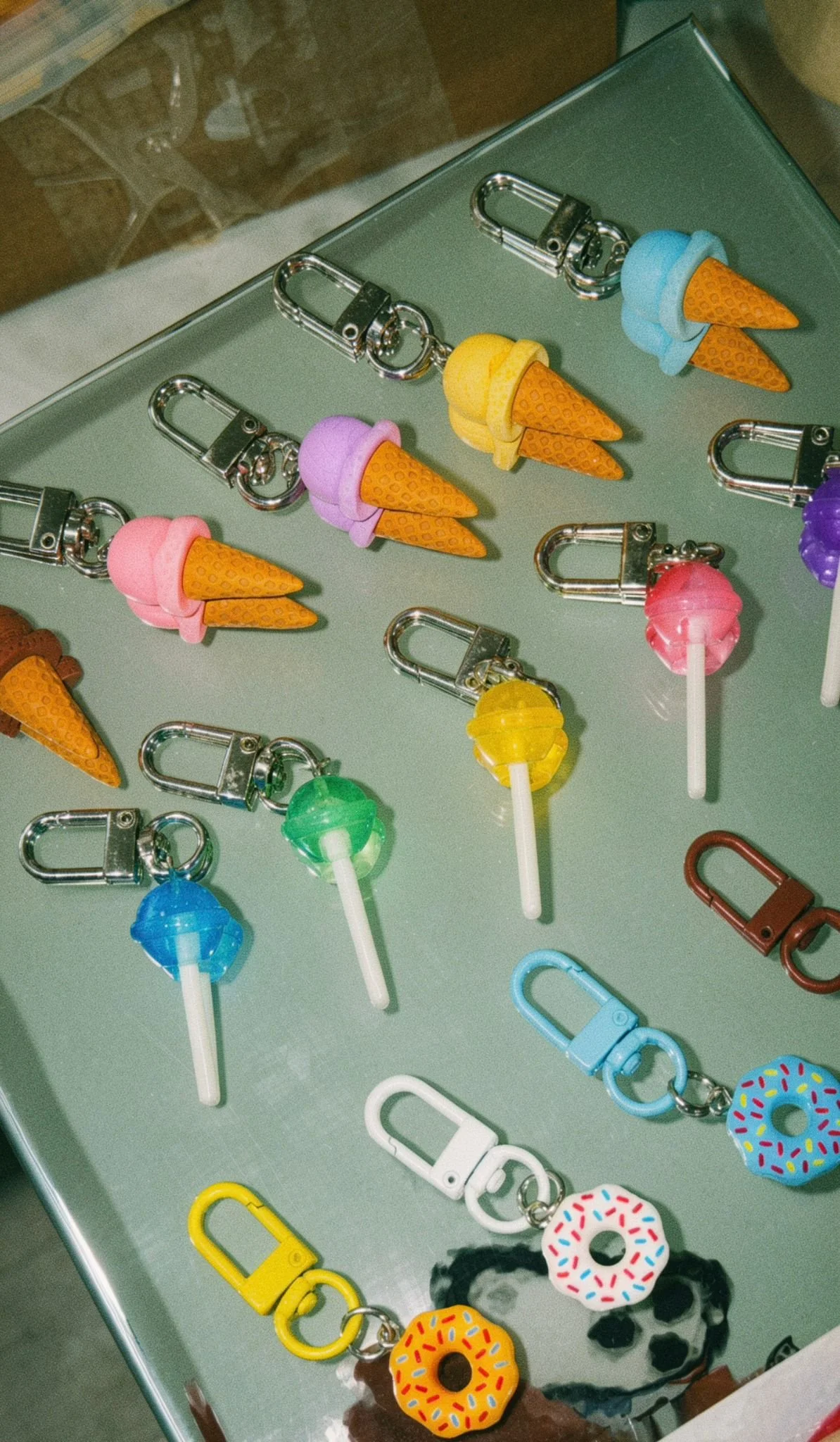 Colorful ice cream cone and donut-shaped keychains with clip hooks on a metallic tray.