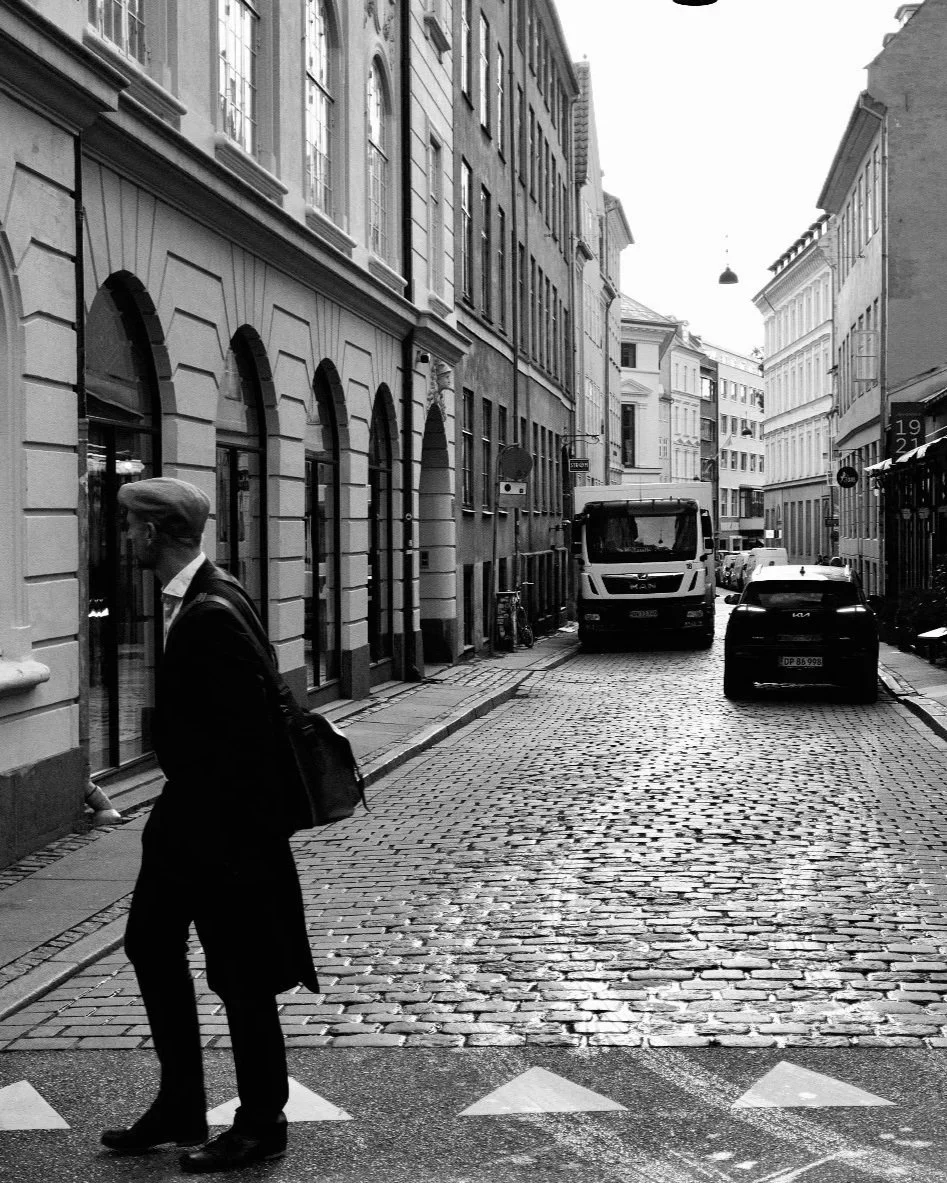 Street photography a Copenaghen: uomo in silhouette che attraversa le strisce pedonali. Fotografia in bianco e nero ad alto contrasto di Jim Veronese.