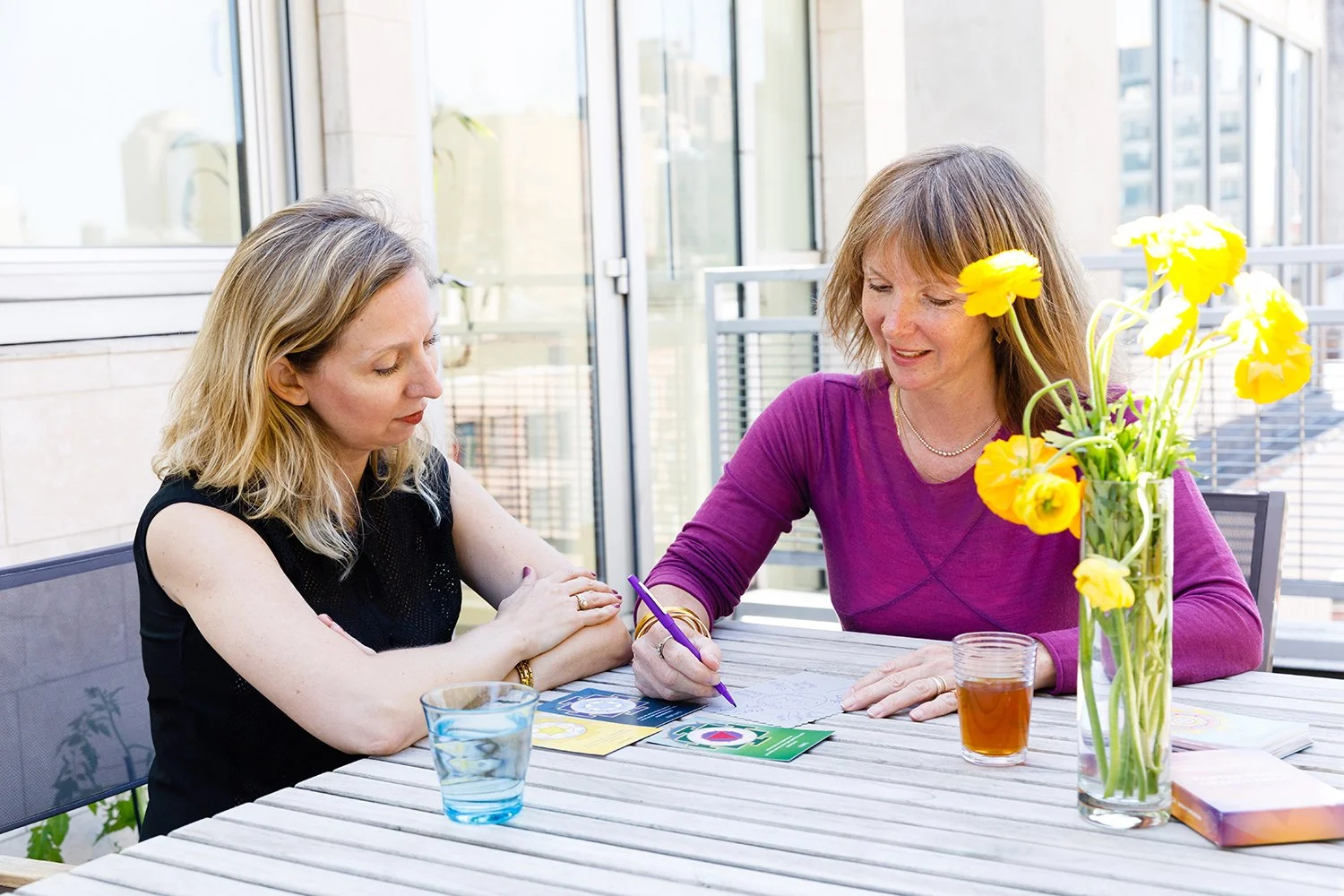 Sarah Yantra giving an ayurvedic astrology consultation. The yellow flowers in the vase and the New York City skyline behind.