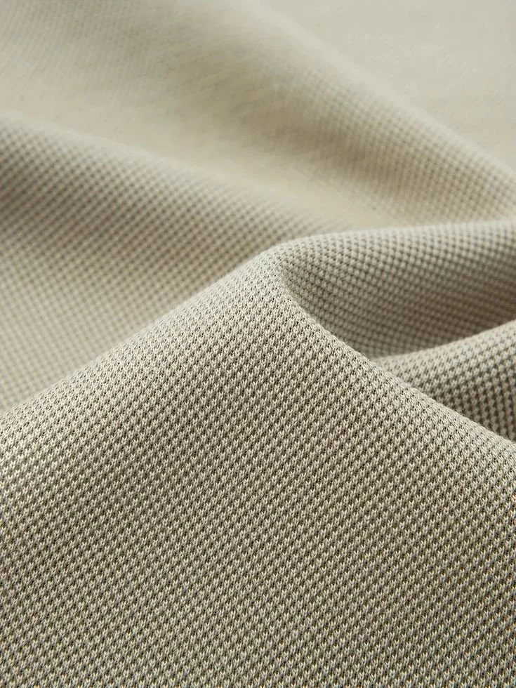 Close-up of beige fabric with a small, textured pattern and slight waves.