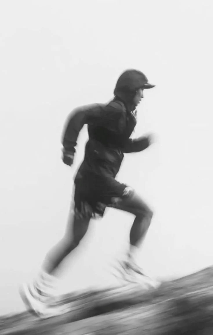 A person running outdoors, dressed in athletic clothing and a helmet, with a blurred background indicating motion.