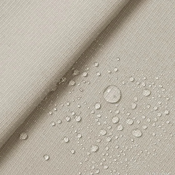 Close-up of a beige fabric surface with water droplets scattered on it.