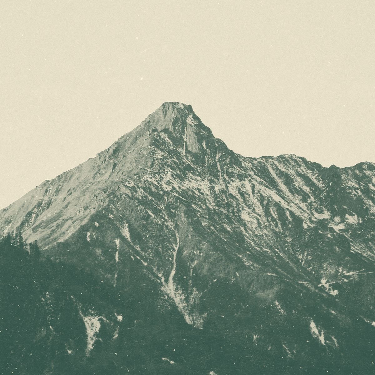 A mountain with a snow-capped peak and rugged terrain in the foreground.