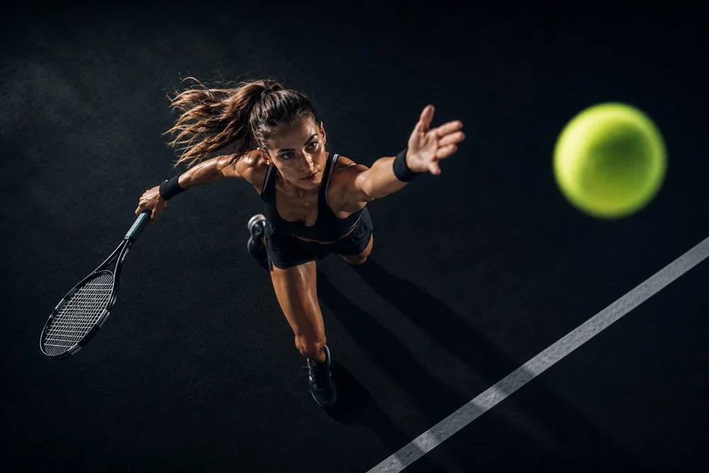 Tennisspielerin beim Schlag auf einem Tennisplatz im dunklen Licht