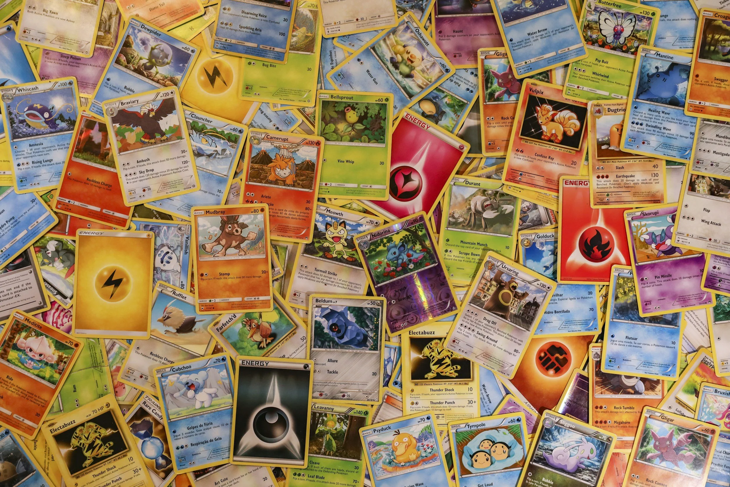 A large pile of Pokémon cards spread out, including various different Pokémon characters and their attack or energy descriptions.