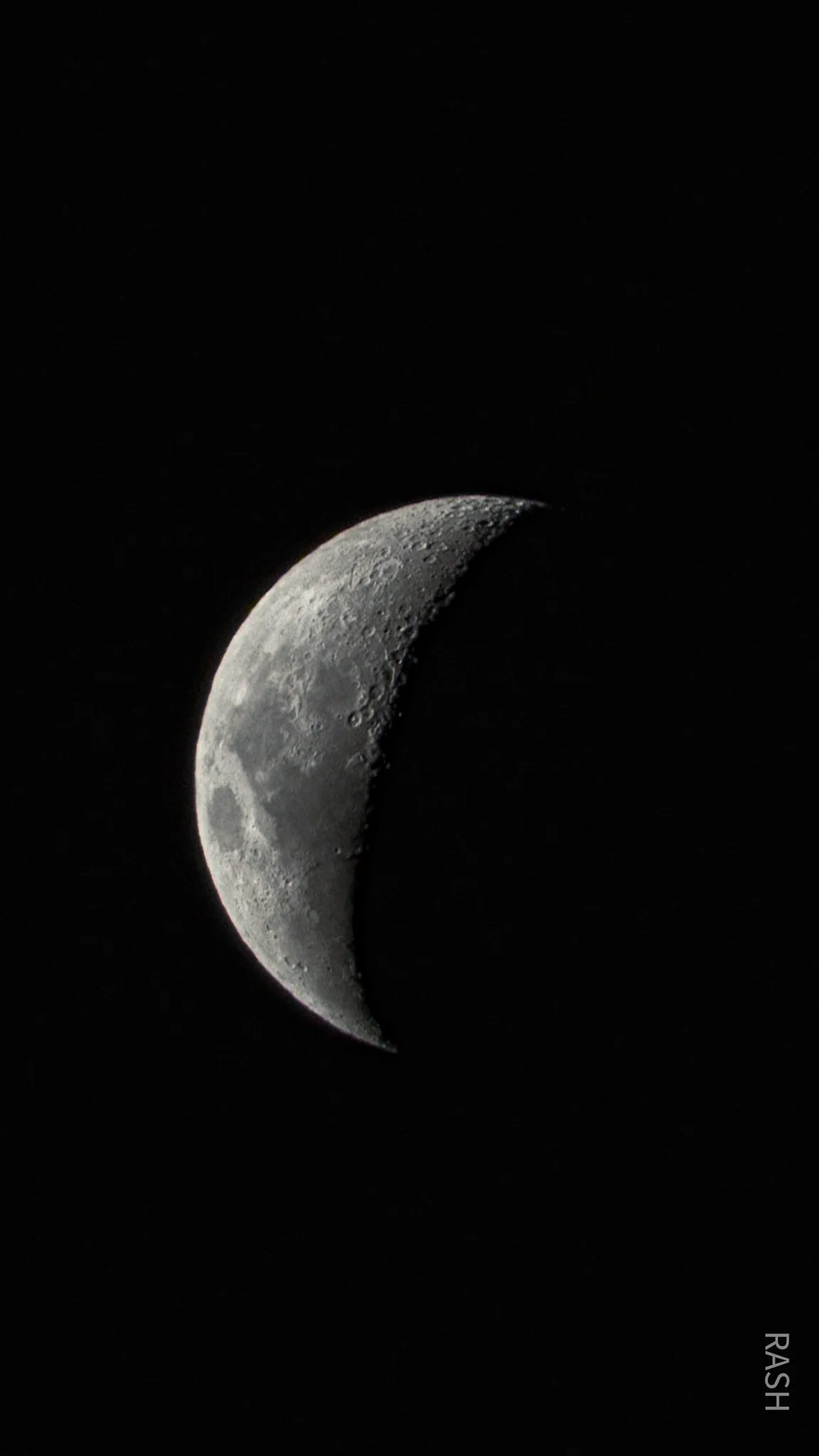 A close-up photograph of the moon's crescent phase against a black background.