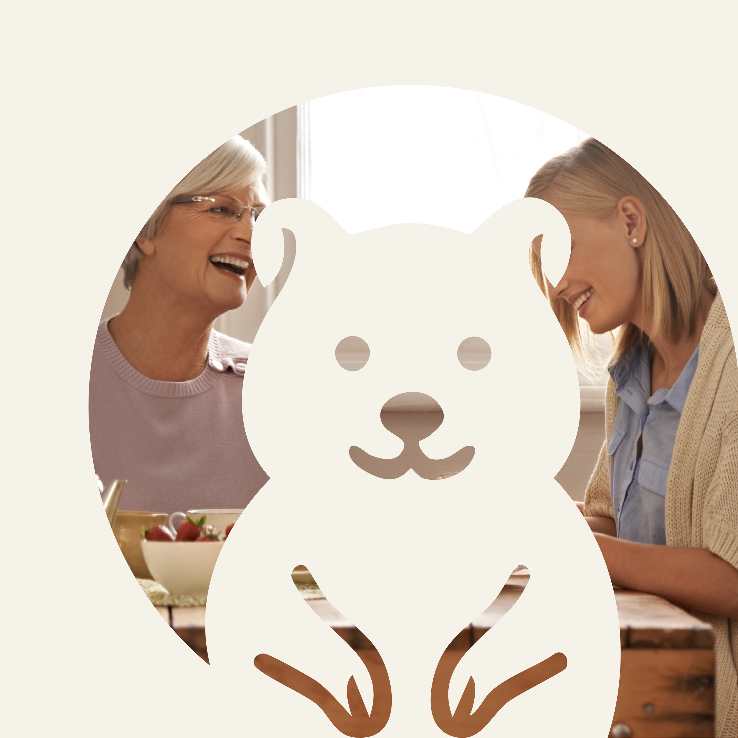 Two women, one elderly with glasses and one young with earrings, smiling at each other and sharing a moment over a table with a bowl of strawberries, in a bright room.