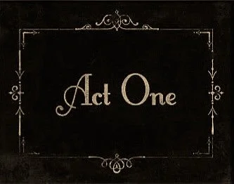 A blackboard or chalkboard with the words 'Act One' written in the center in cursive font, framed with decorative borders.