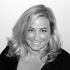Black and white photo of a smiling woman with shoulder-length wavy hair.