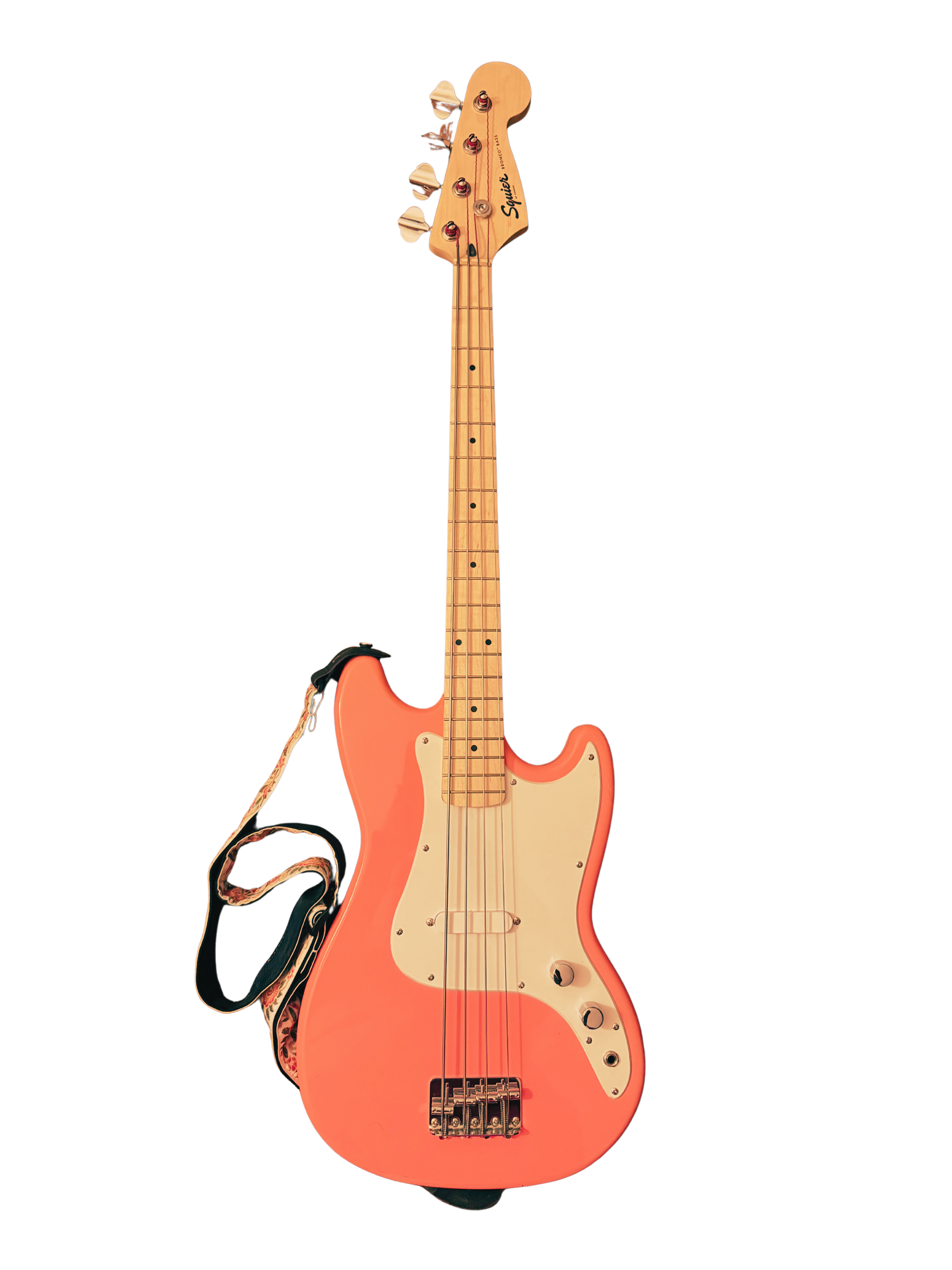 A pink electric bass guitar with a white pickguard, four strings, and tuning pegs on a wooden headstock.