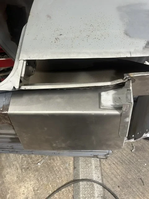 A close-up of a stainless steel industrial or commercial kitchen appliance, with visible scratches and a slightly bent metal piece on top.